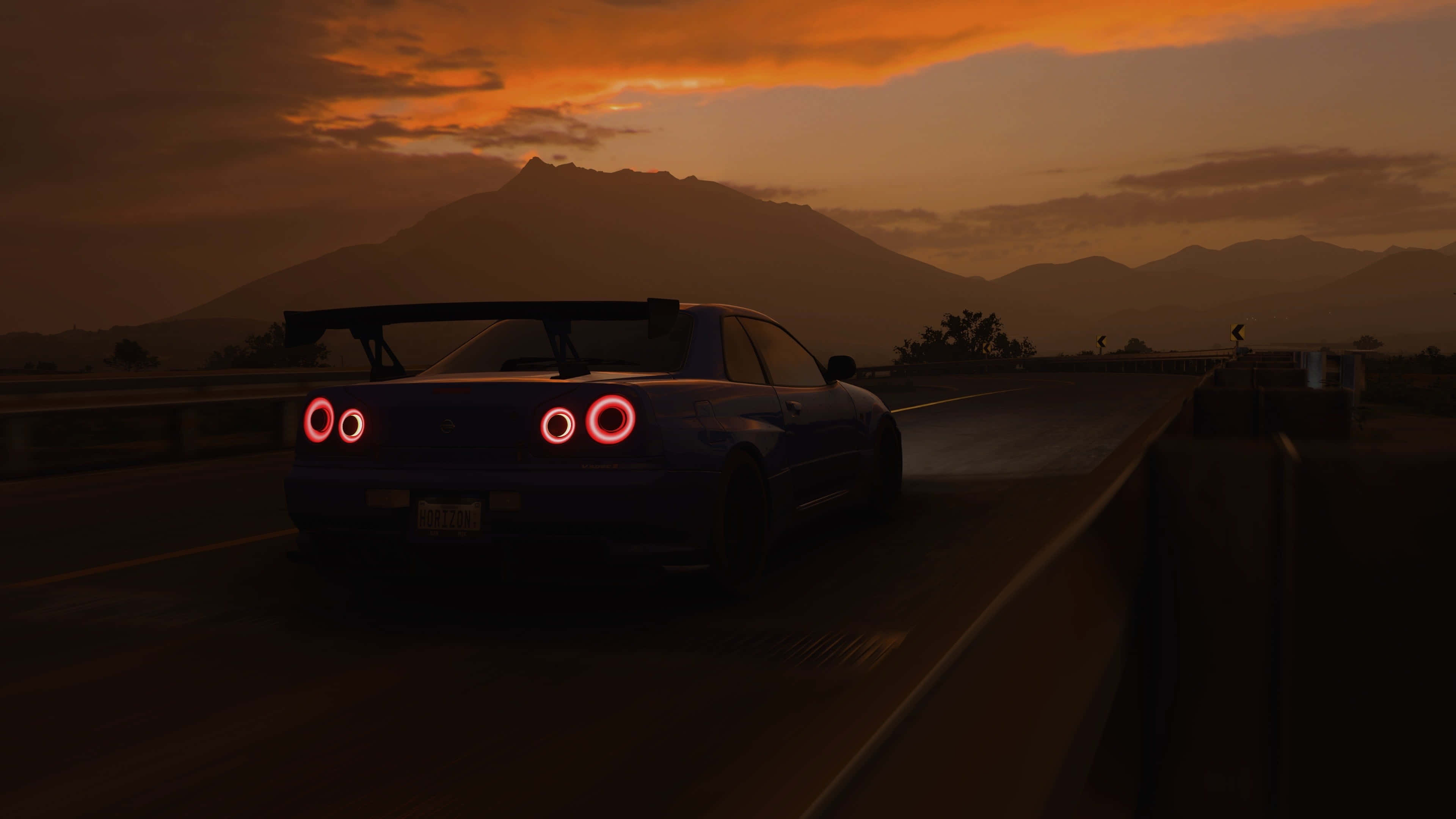 Forza Horizon 桌布 壁紙 — 一輛藍色跑車帶著發光的紅色圓形尾燈，在日落時分行駛在高速公路上，背景是山脈。