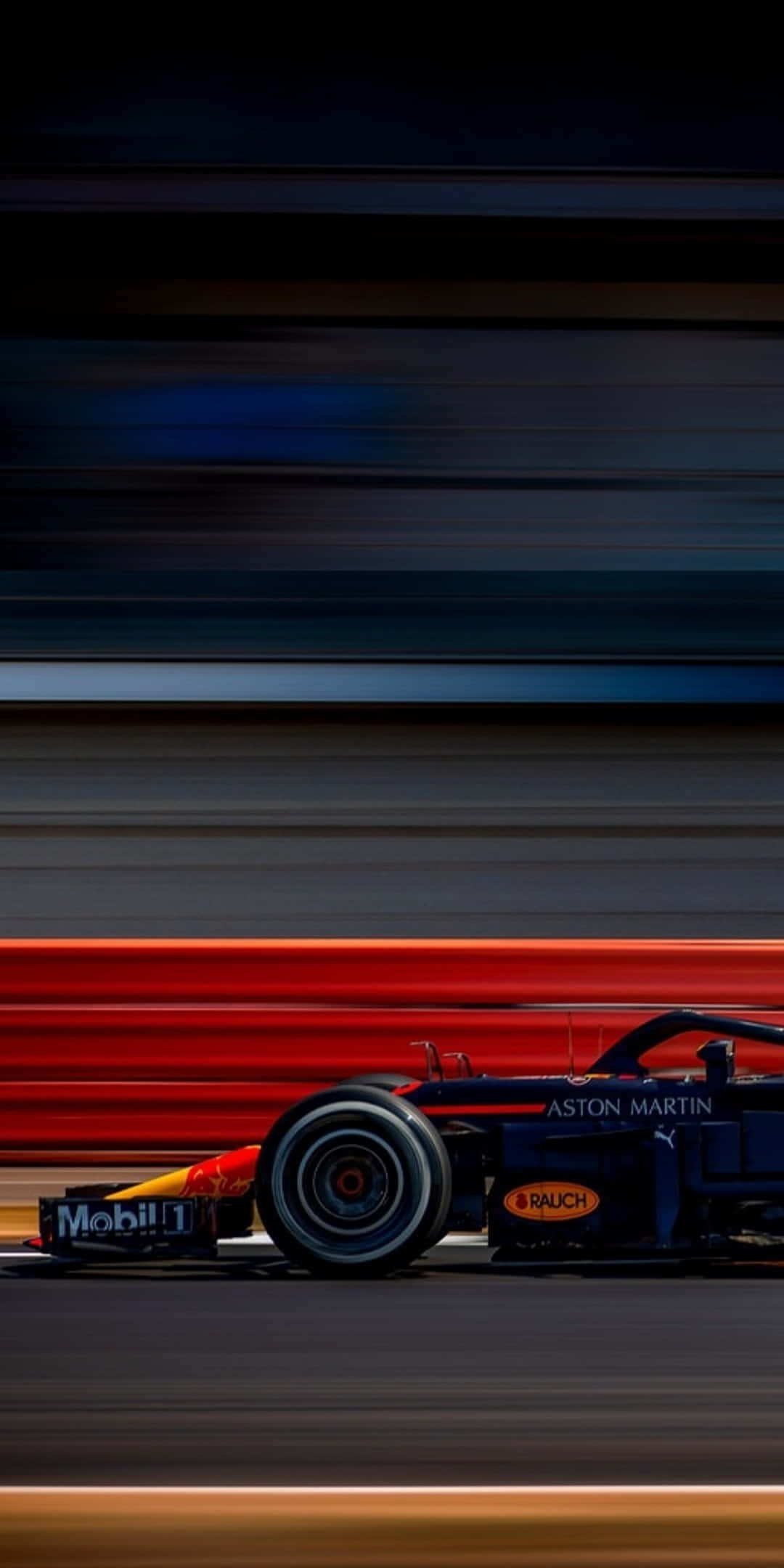 F1 桌布 壁紙 — 一輛藍色阿斯頓馬丁F1賽車在黑暗的賽道上高速駛過，留下紅色和橙色的模糊痕跡。