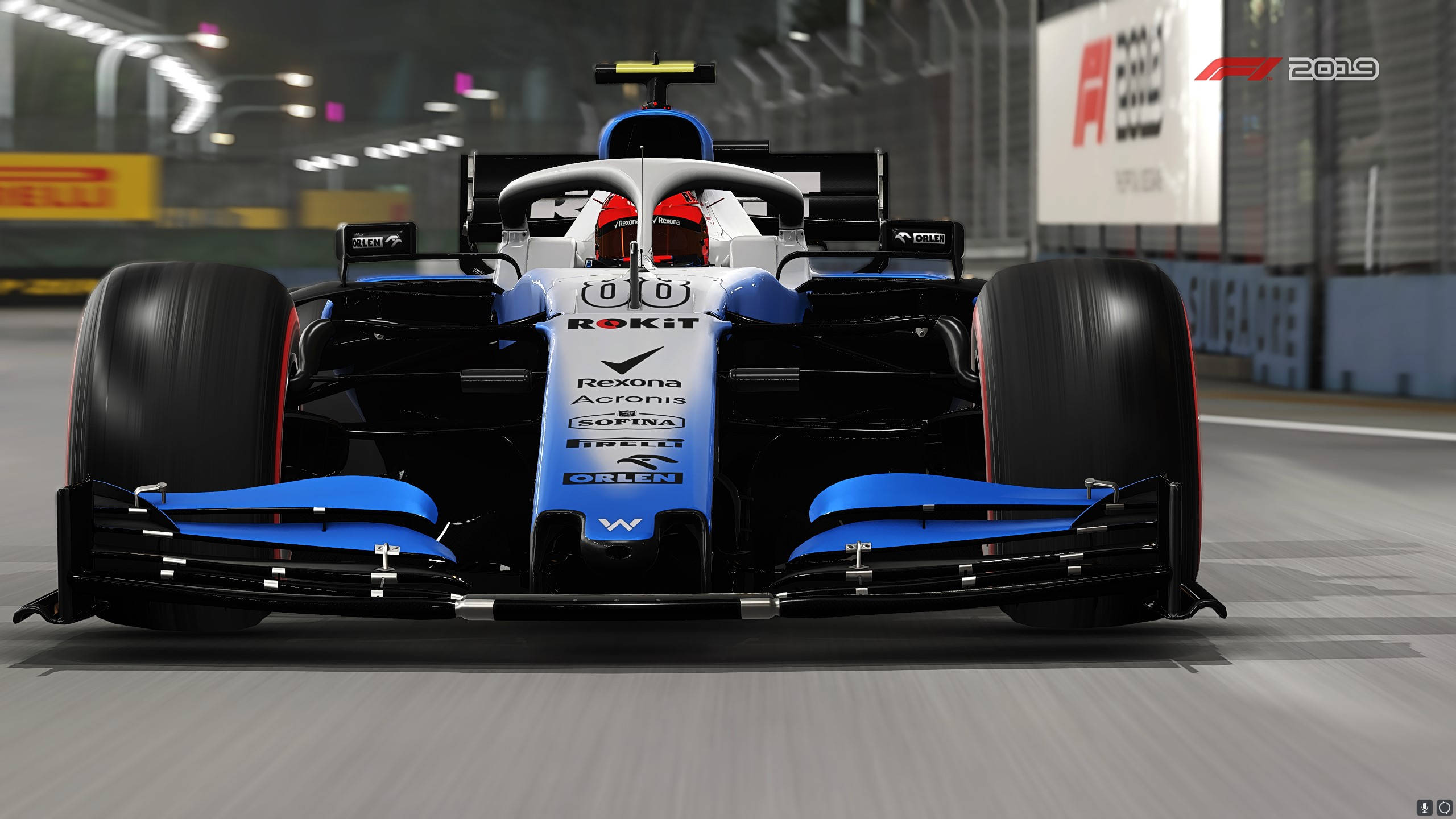 F1 2019 壁紙 桌布 壁紙 — 一輛藍黑相間的F1賽車在明亮人造燈光下於賽道上疾馳的正面視角。