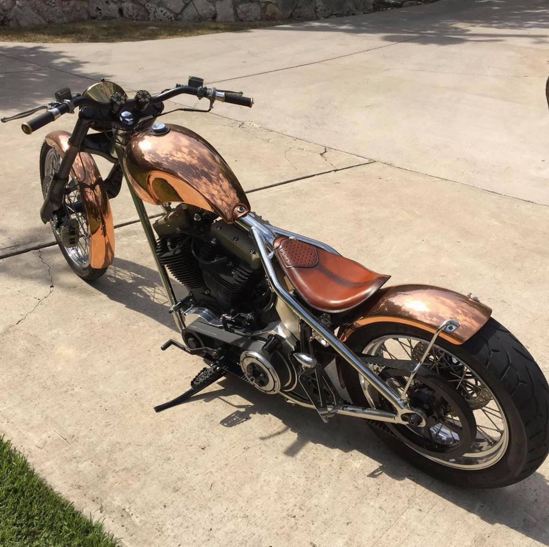 Choppers 桌布 壁紙 — 一輛訂製的chopper摩托車，油箱和擋泥板塗成銅色，停在陽光普照的混凝土車道上。