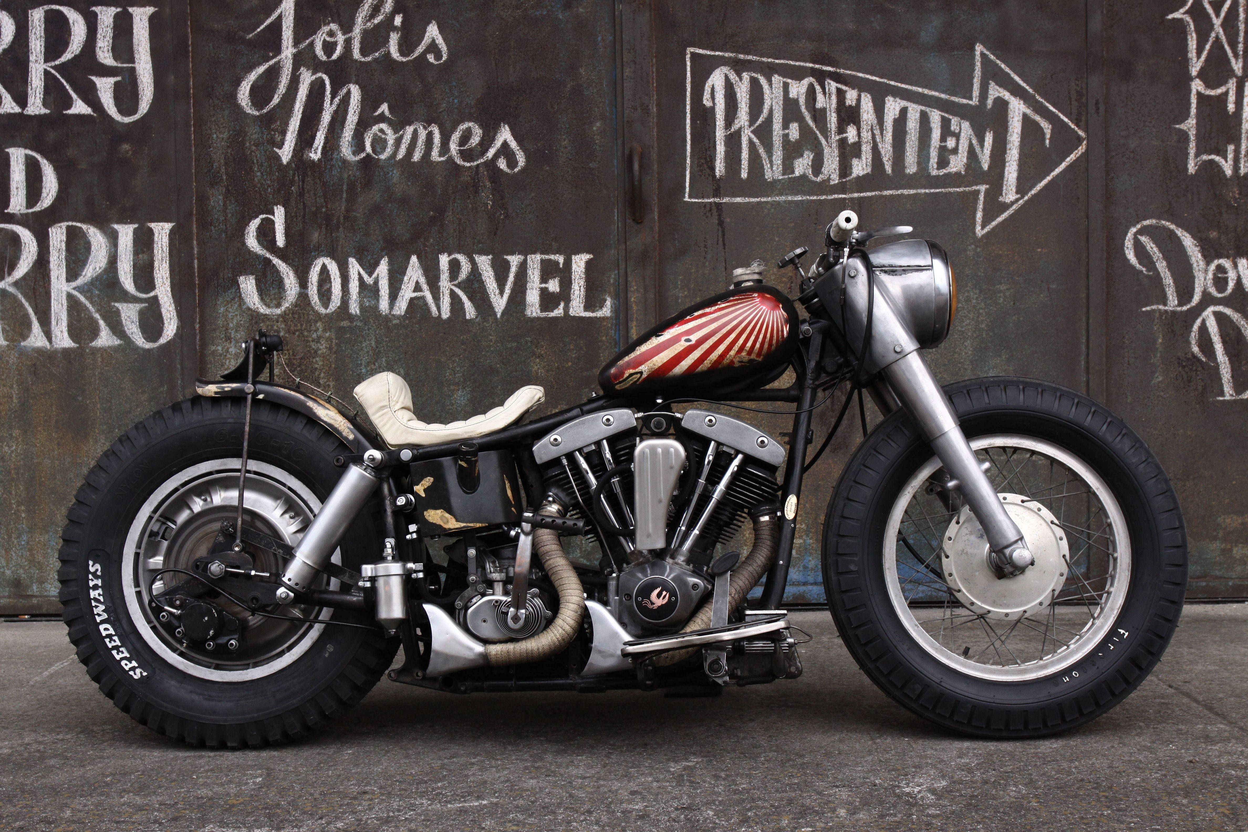 Bobber 桌布 壁紙 — 一輛訂製的chopper摩托車，帶有紅色太陽光紋的油箱，停在佈滿粉筆的金屬牆前。