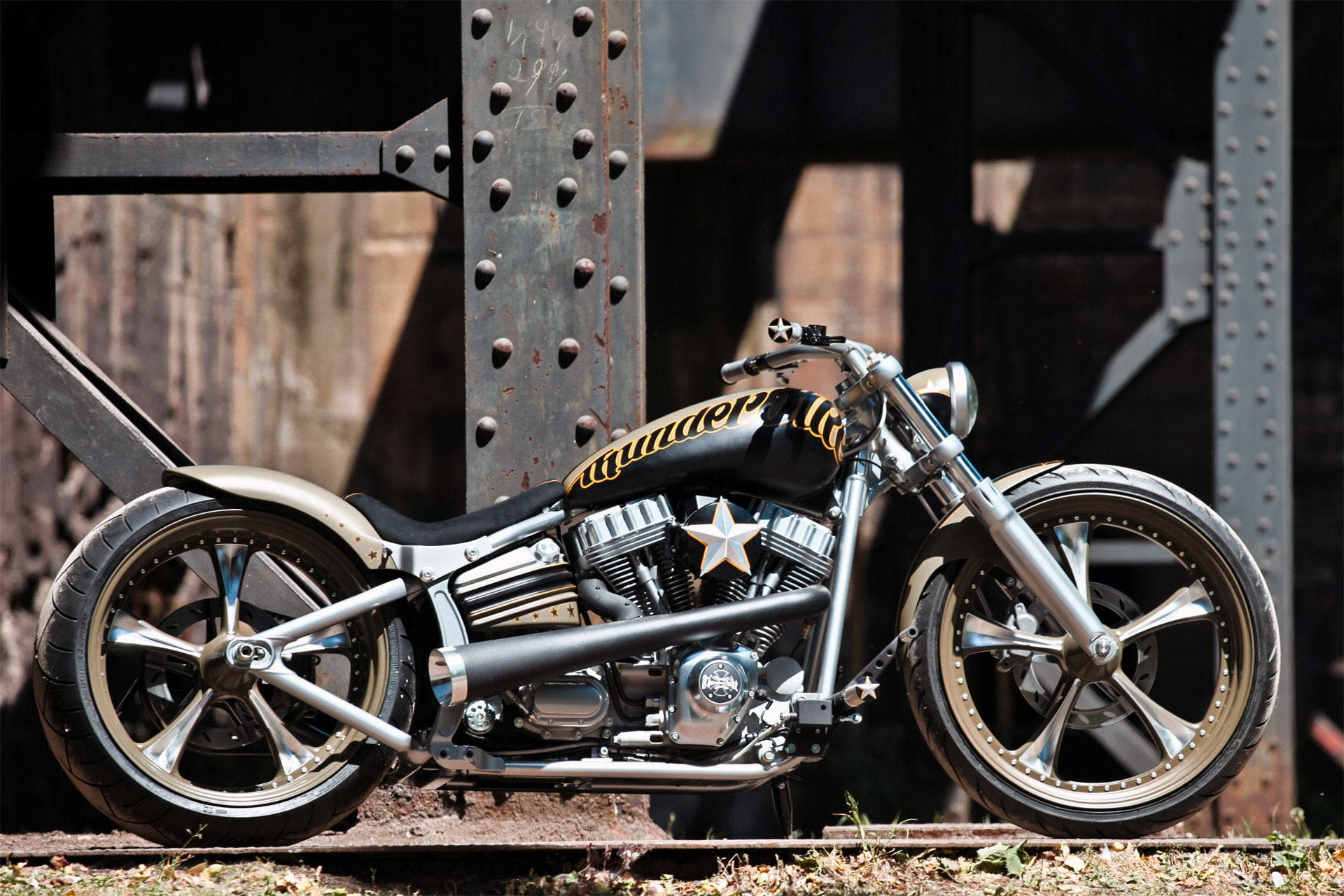 Bobber 桌布 壁紙 — 一輛訂製的chopper機車，帶有鍍鉻裝飾和星星貼紙，停在生鏽的鋼橋下方的火車軌道上。