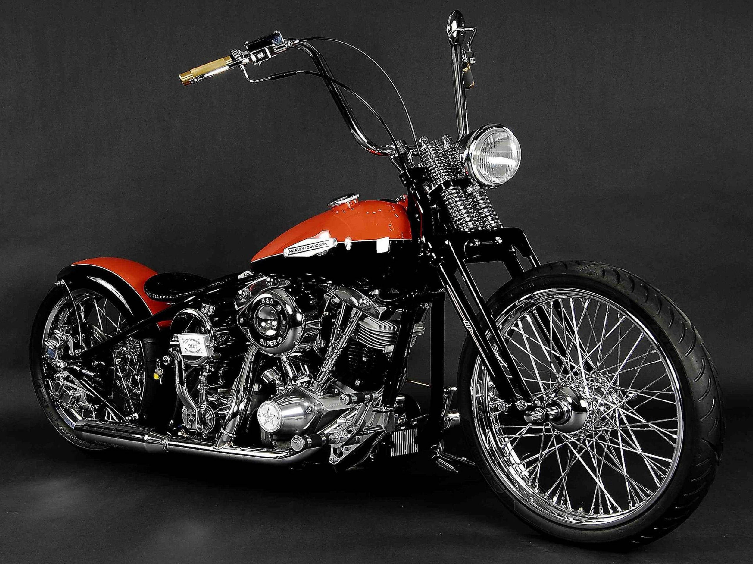 Harley 桌布 壁紙 — 一輛訂製的chopper機車，配有紅色油箱和鍍鉻細節，在黑暗的工作室背景下擺好姿勢。
