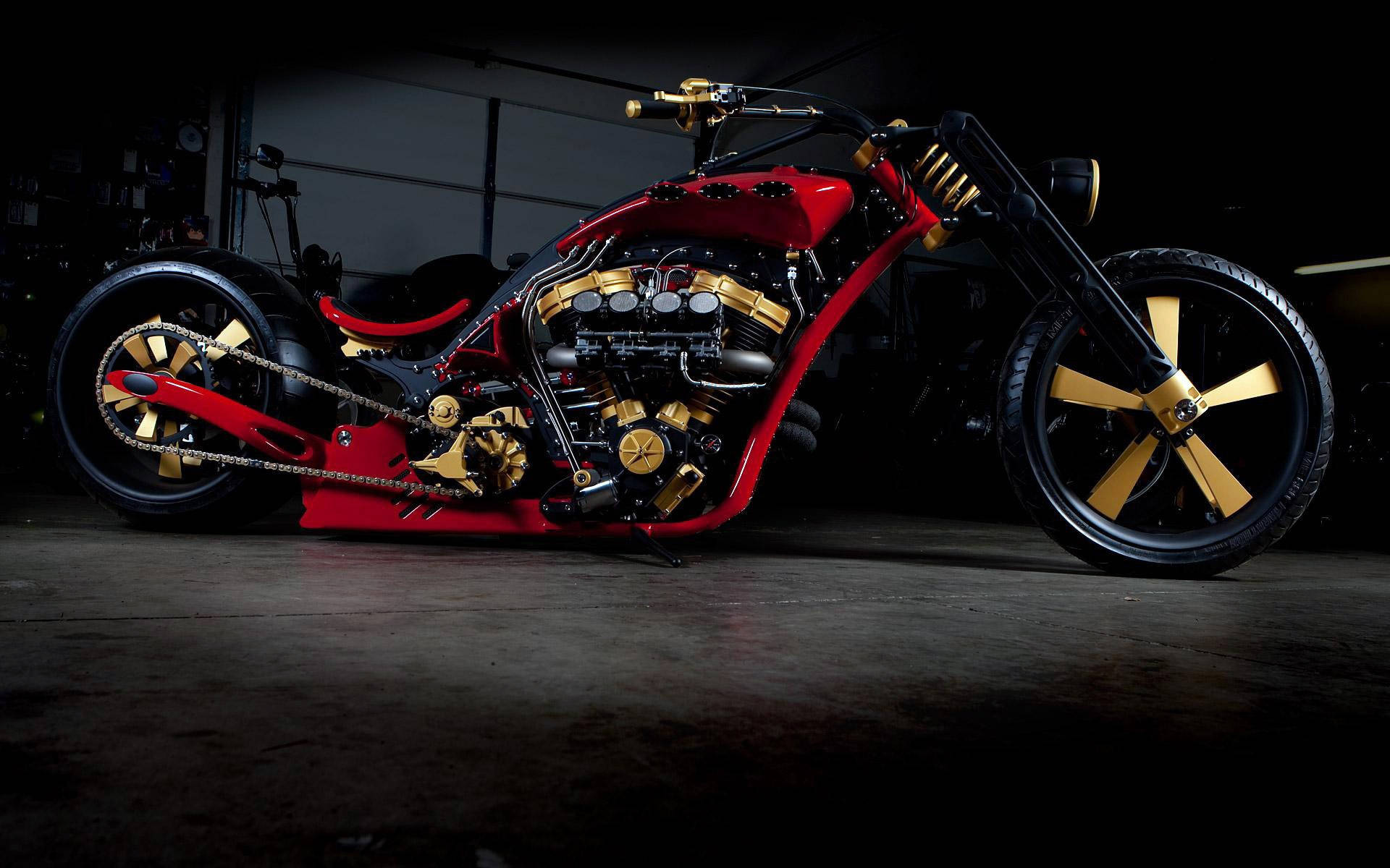 Bobber 桌布 壁紙 — 一輛訂製的紅金色chopper機車，配備外露引擎和鋼絲輪圈，在黑暗的車庫中被戲劇性地照亮。