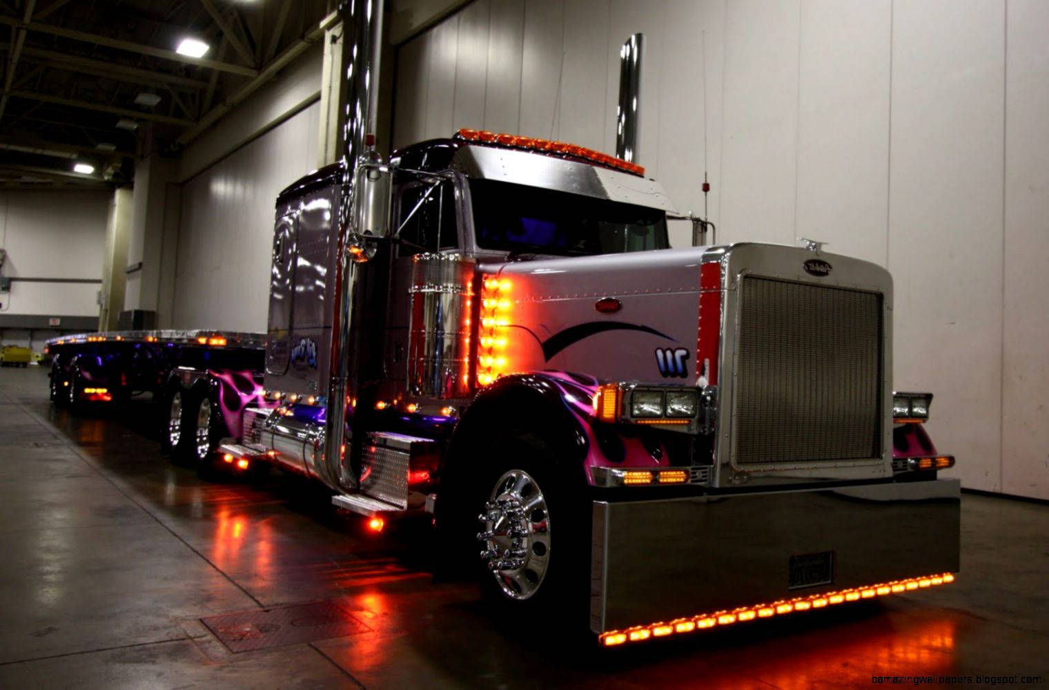 Trucks 桌布 壁紙 — 一輛訂製的鍍鉻半掛卡車，帶有發光的橙色燈光和紫色火焰貼花，停在倉庫內。