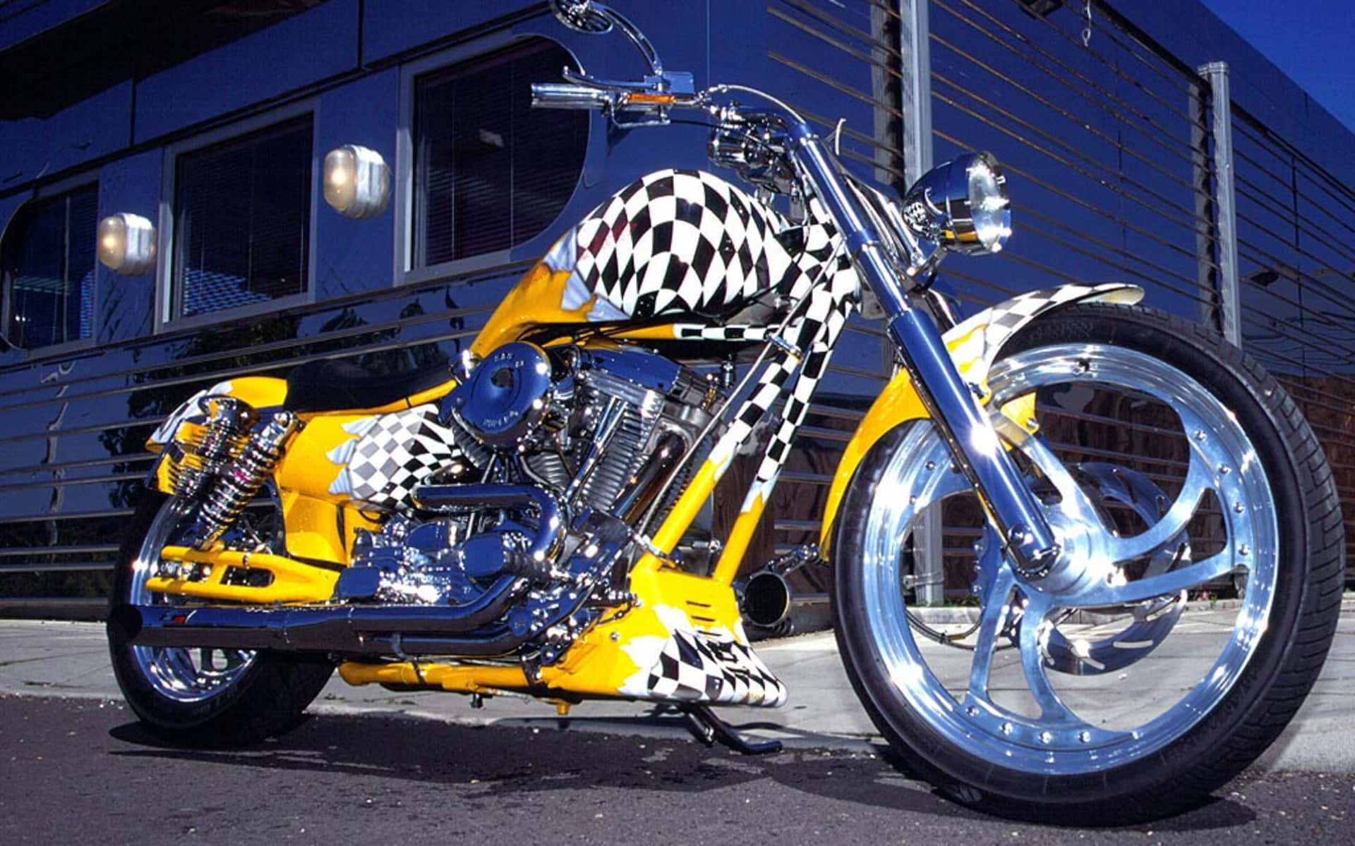 Harley Davidson Motorcycle 桌布 壁紙 — 一輛訂製的黃黑格子chopper機車，帶有鍍鉻裝飾，停放在現代建築附近的人行道上。