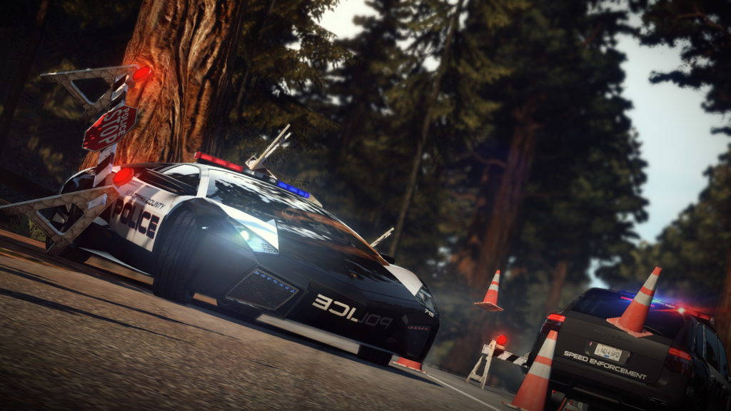 Need For Speed 桌布 壁紙 — 一輛警用跑車在森林道路上撞上一棵樹，伴有閃爍的燈光和交通錐。