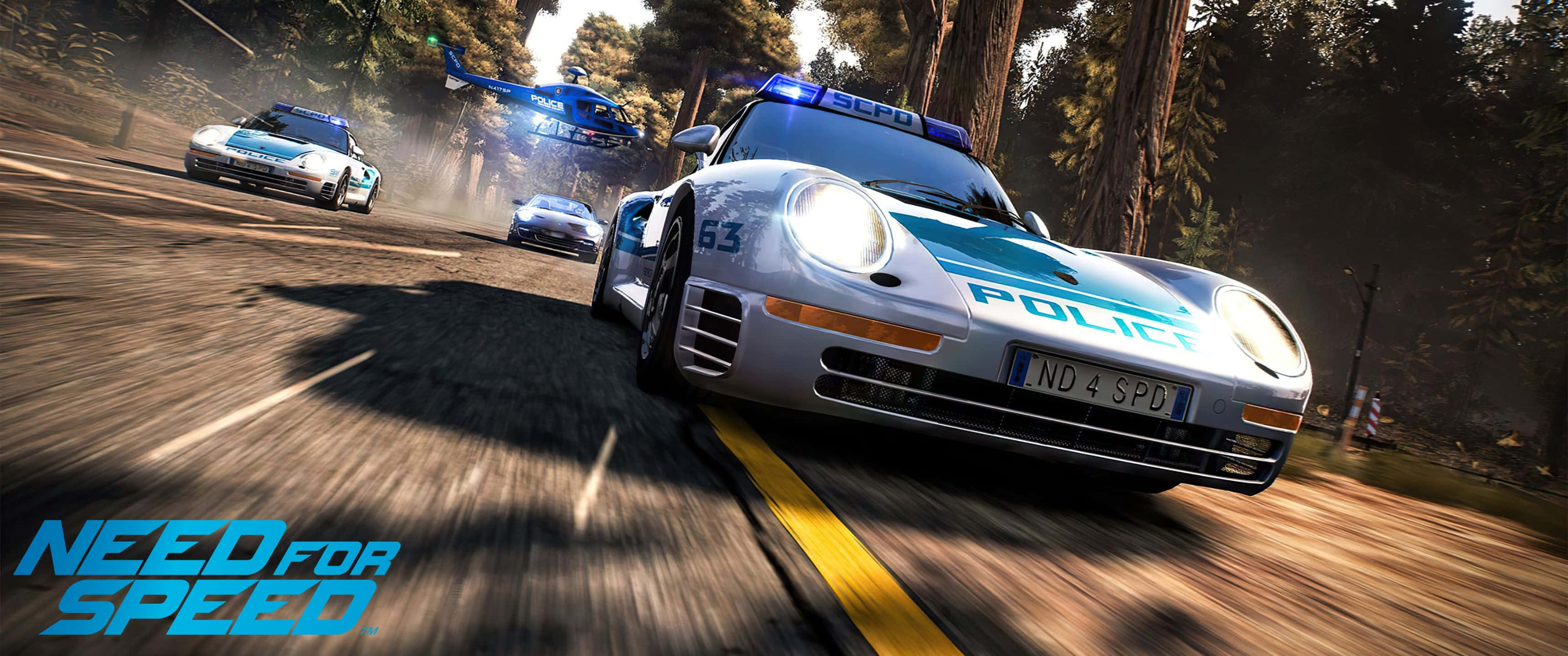 3440x1440p Need For Speed 桌布 壁紙 — 一輛警用跑車在森林道路上高速行駛，直升機和其他車輛在高速賽車場景中追逐。
