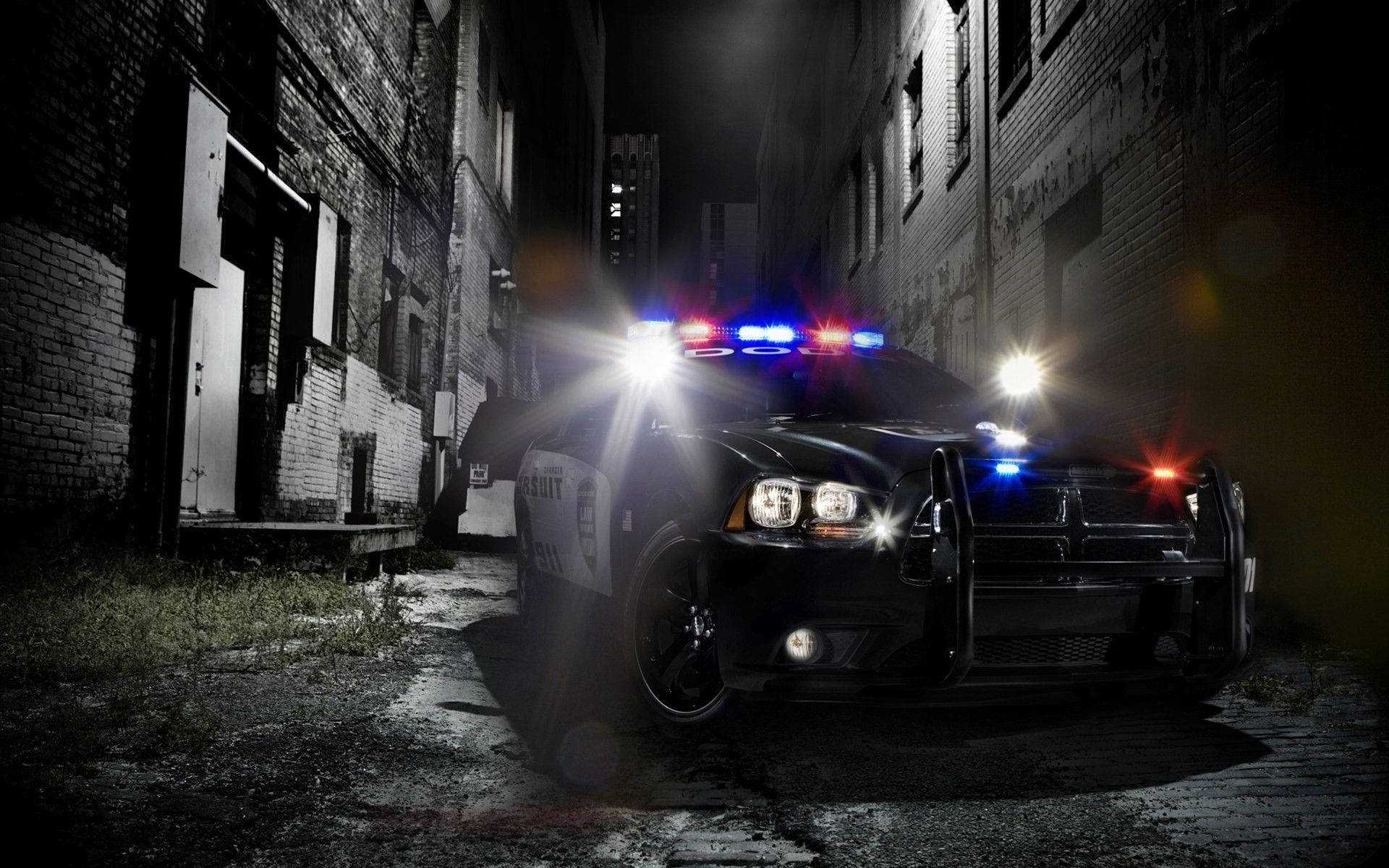 美學 桌布 壁紙 — 一輛警車閃爍著紅藍燈光，在夜晚主導了磚造建築之間一條狹窄陰暗的小巷。