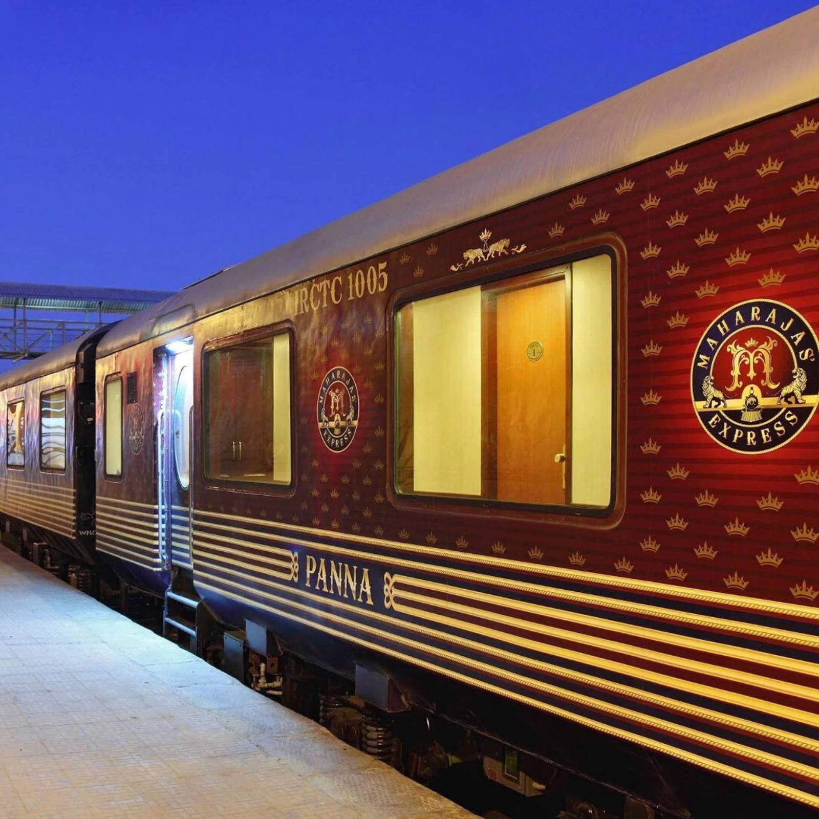火車 桌布 壁紙 — 一輛豪華的Maharajas Express列車車廂在暮色中閃耀，金色皇冠和溫暖的內部燈光透過窗戶發光。