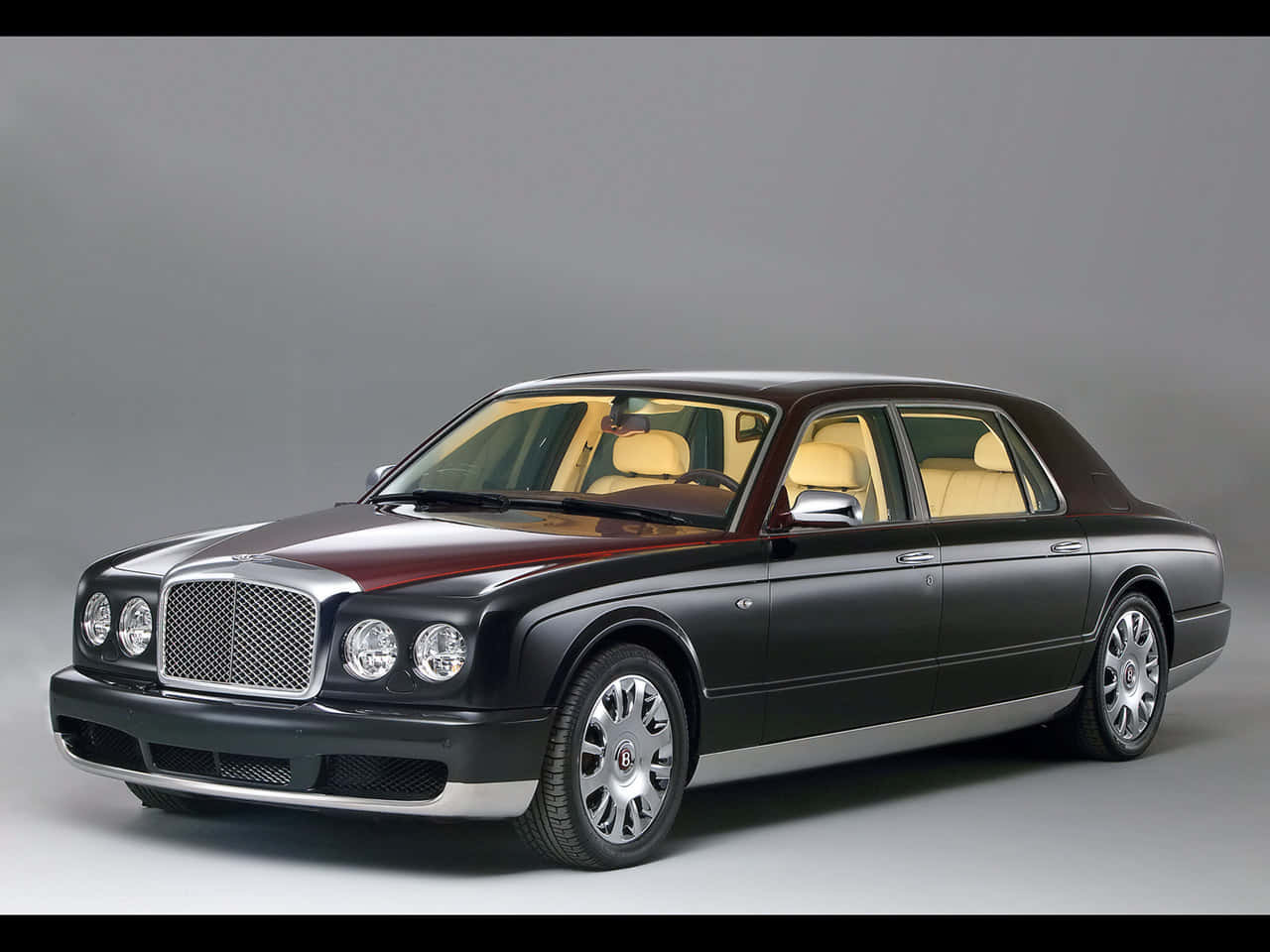 Bentley Arnage 桌布 壁紙 — 一輛豪華的賓利轎車，採用雙色黑色和酒紅色塗裝及奶油色皮革內飾，在工作室環境中展示。