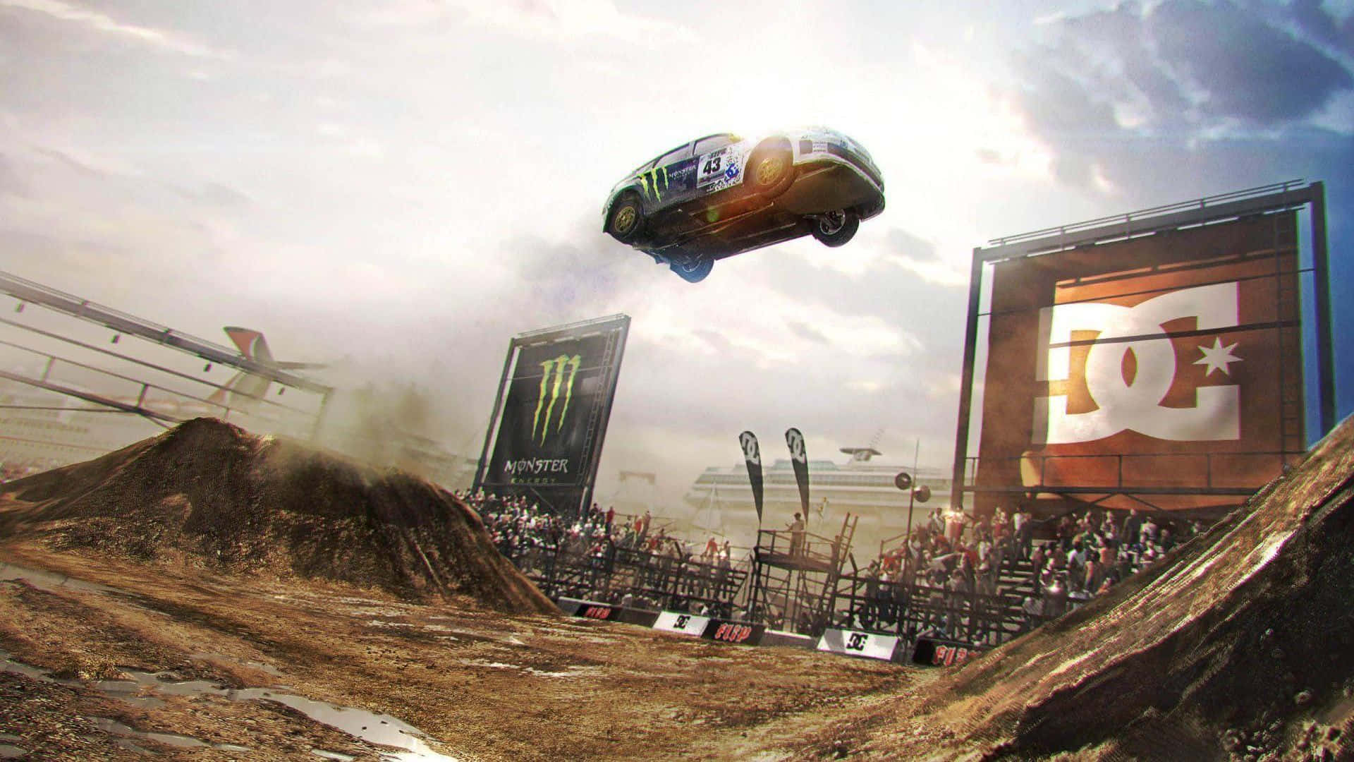 1080p Dirt 3 桌布 壁紙 — 一輛賽車在泥地賽道上空飛翔，觀眾在陰天下的看台上觀看。