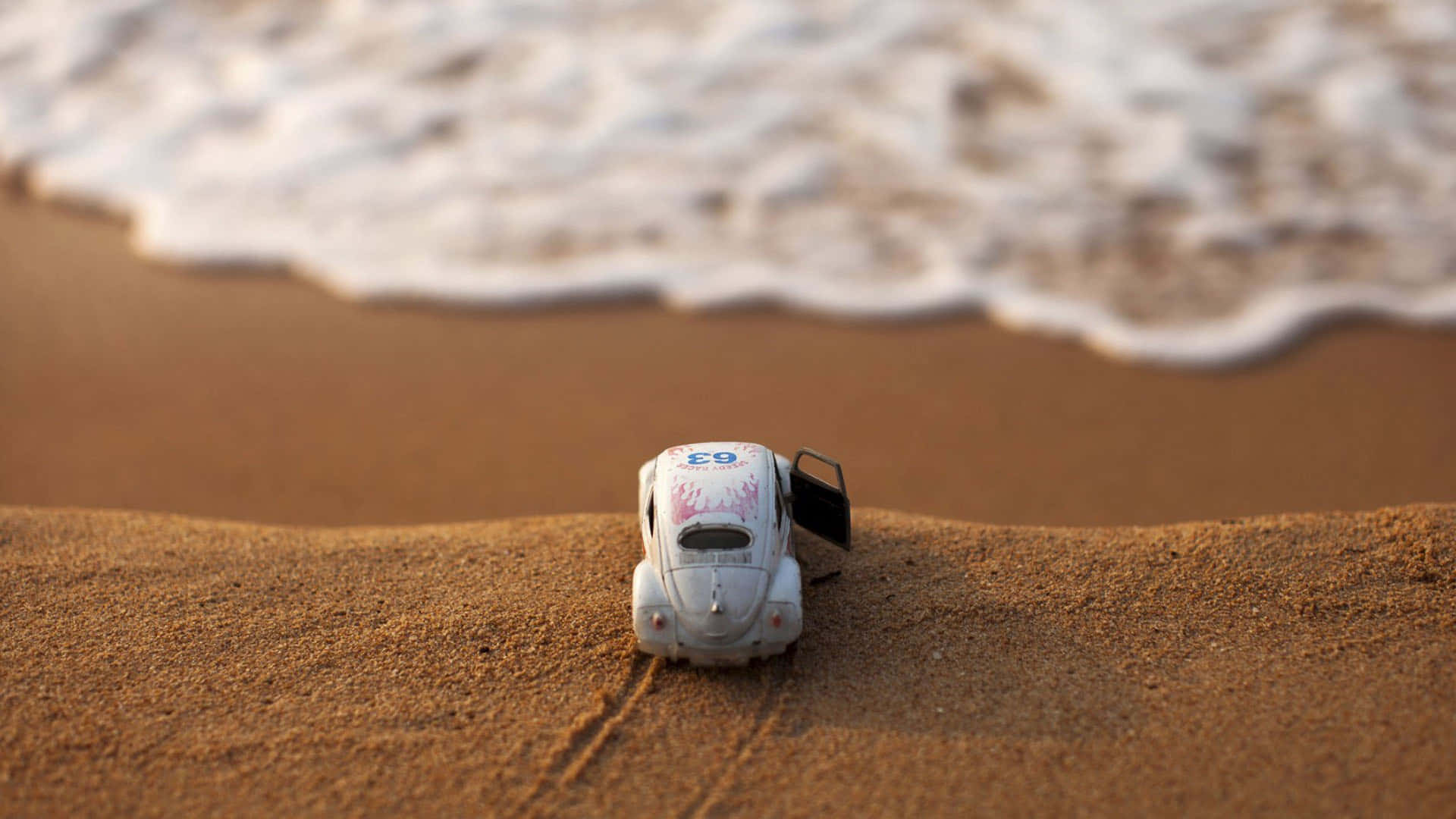 sand 桌布 壁紙 — 一輛車門打開的迷你白色復古車停在金色沙灘上，背後有溫柔的海浪湧來。