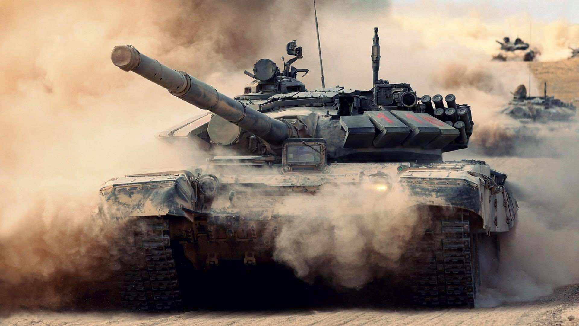 坦克 桌布 壁紙 — 一輛軍用坦克在塵土飛揚的沙漠戰場上向前衝鋒，履帶周圍煙霧繚繞。