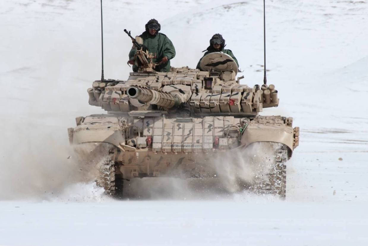 印度軍隊 桌布 壁紙 — 一輛軍用坦克載著兩名士兵在雪地上高速行駛，濺起雪花。