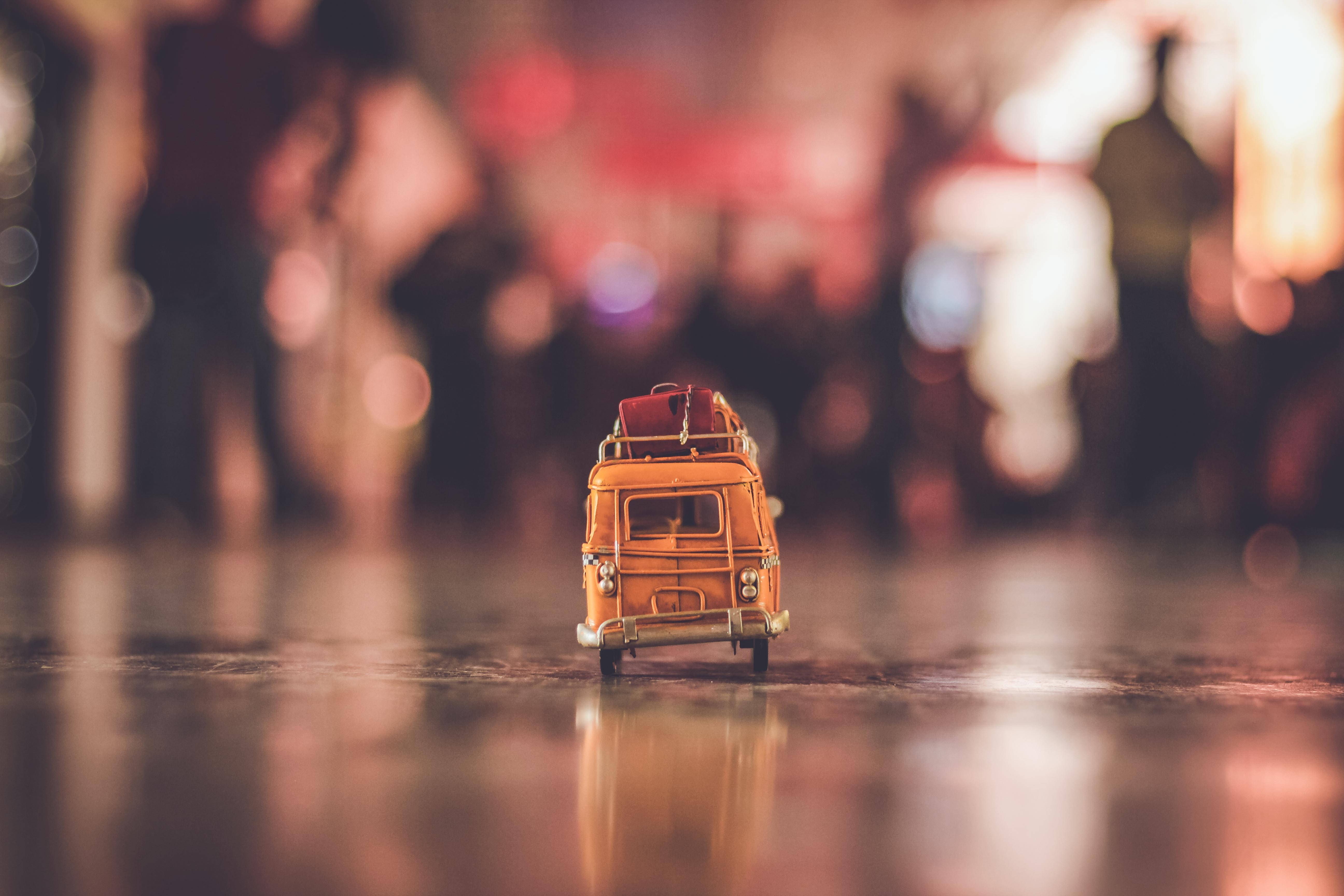 Alone 桌布 壁紙 — 一輛迷你橙色復古貨車，車頂載有行李，在夜間溫暖的散景燈光下停在潮濕的路面上。