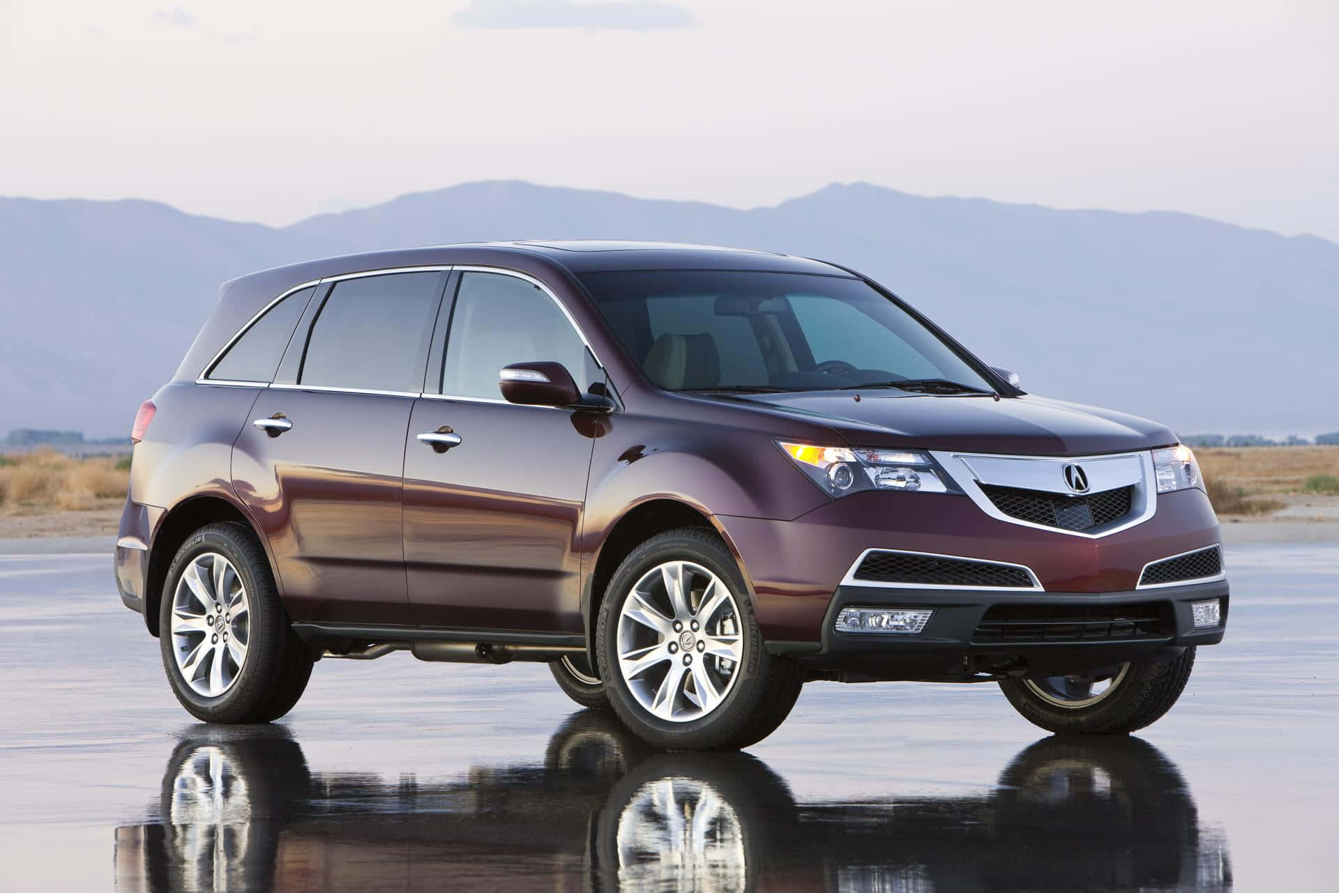 Acura 桌布 壁紙 — 一輛酒紅色的Acura SUV在潮濕的瀝青路面上反射，遠山在柔和天空下。