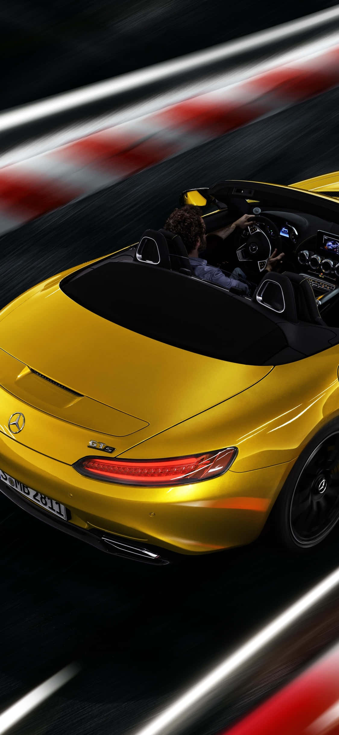 跑車 桌布 壁紙 — 一輛金色Mercedes-AMG GT R敞篷跑車在賽道上疾馳，帶有模糊的紅白路緣和動態線條。