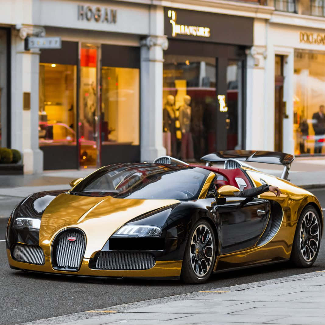 Store 桌布 壁紙 — 一輛金色和黑色的Bugatti Veyron停泊在城市的街道上，背景是豪華精品店。