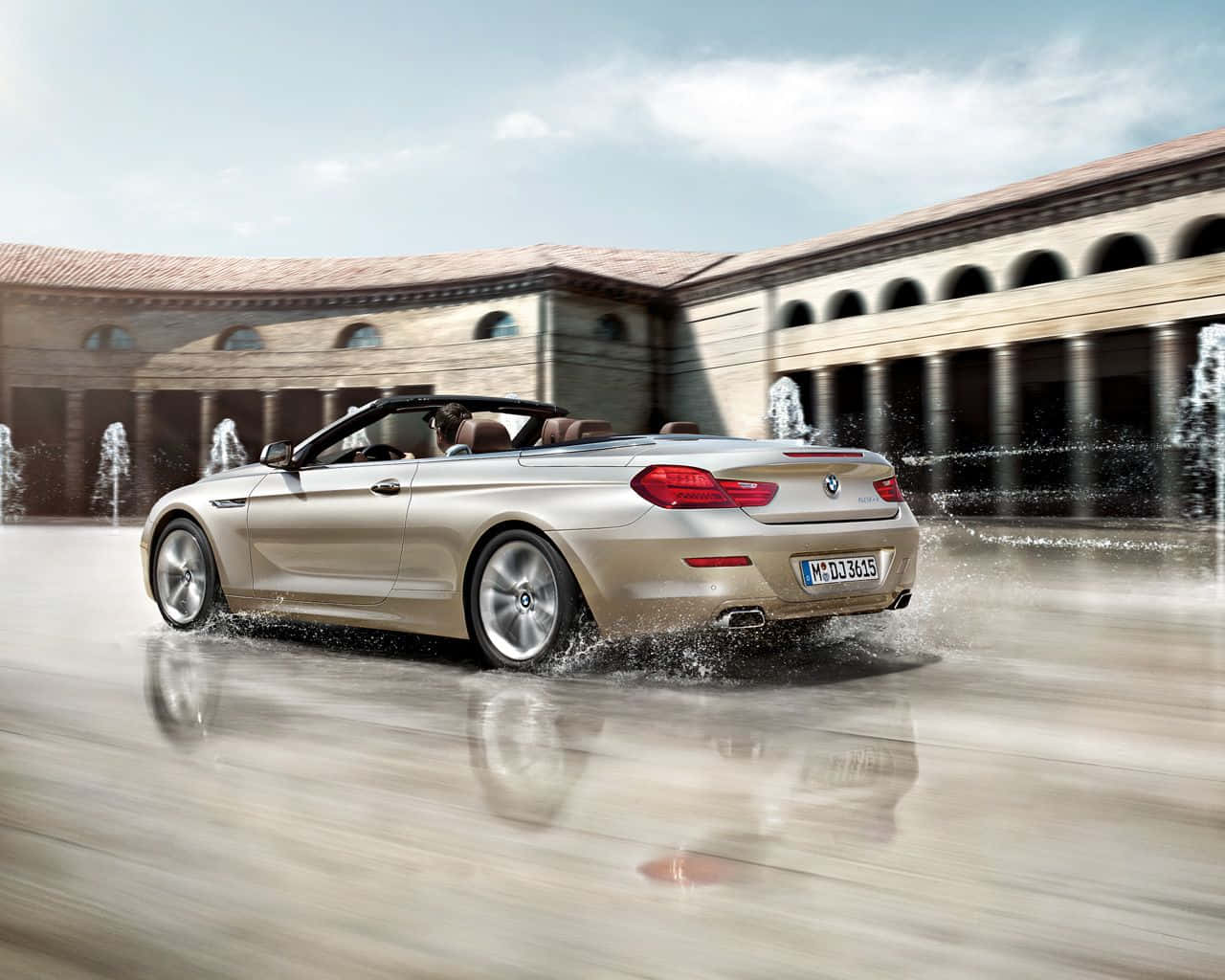 Bmw 6 Series 桌布 壁紙 — 一輛金色敞篷跑車在濕漉漉的庭院中疾馳，濺起水花，噴泉在古典建築後方噴灑。