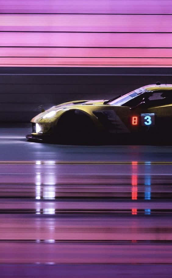 Pixel 3 Grid Autosport 桌布 壁紙 — 一輛金色賽車在霓虹燈下疾馳而過，紫色和粉紅色的條紋照亮了潮濕的賽道。