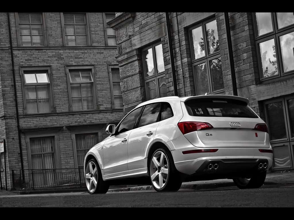 Audi Sq5 桌布 壁紙 — 一輛銀色 Audi Q5 SUV 停泊在磚建築街道上，呈現黑白對比。
