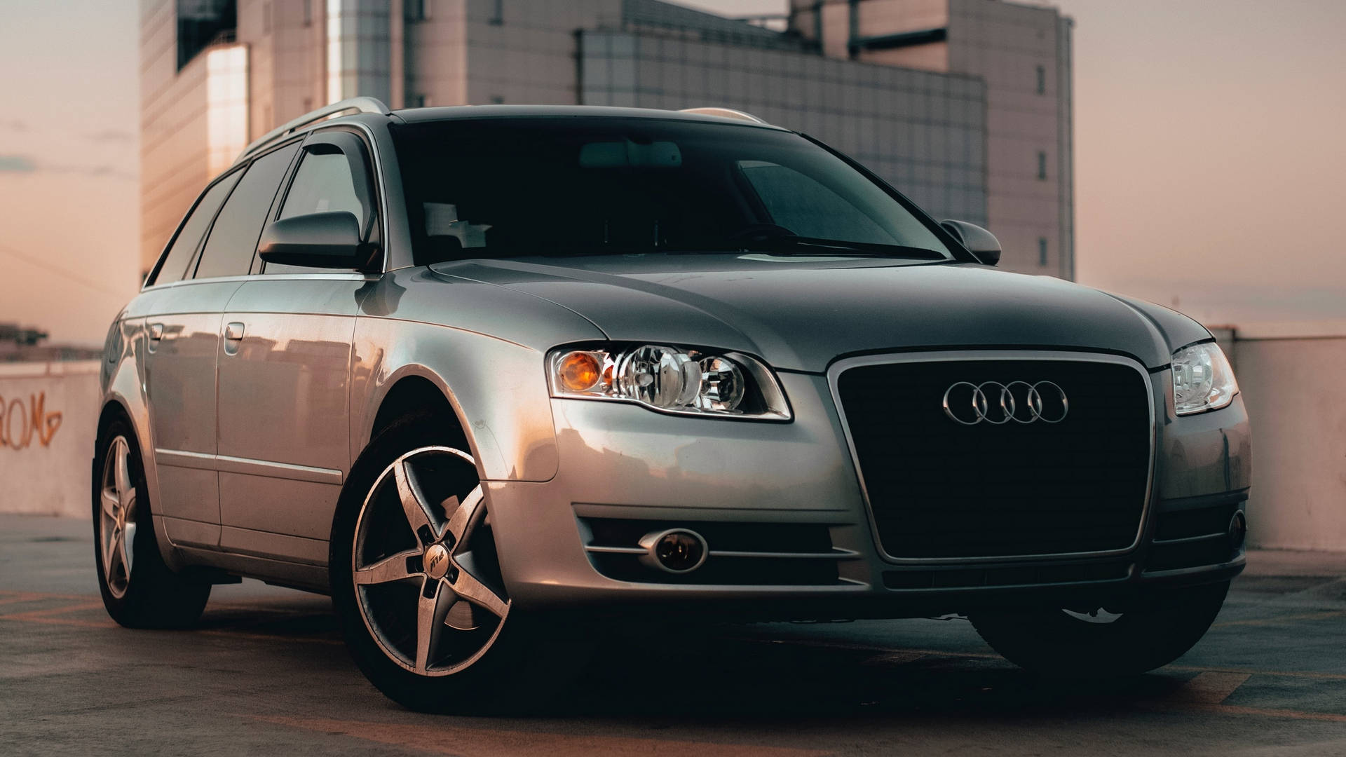 cars 桌布 壁紙 — 一輛銀色 Audi 旅行車在日落時停泊在屋頂上，周圍有溫暖的環境光。