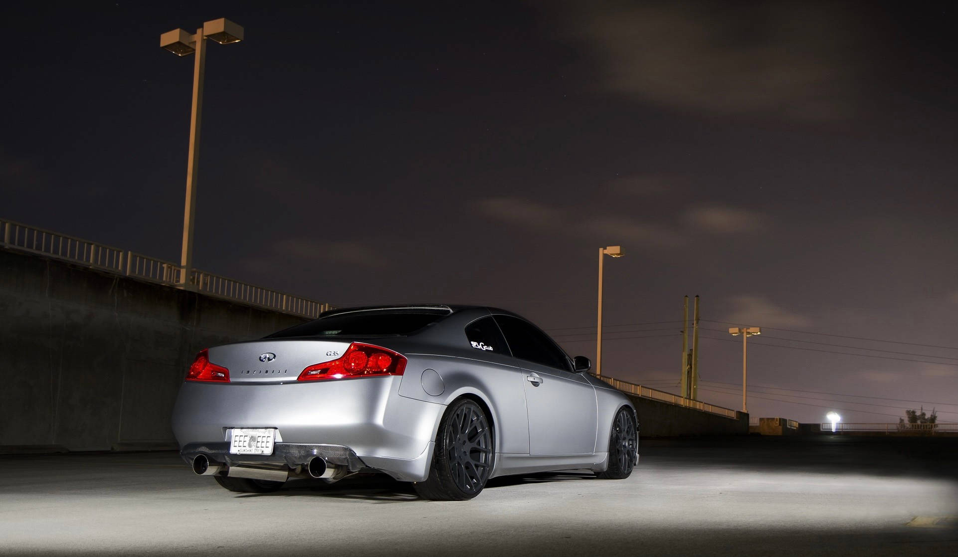 Infiniti 桌布 壁紙 — 一輛銀色 Infiniti G Coupe 在夜間停放在空蕩蕩的混凝土停車場上，在人造燈光下閃閃發光。