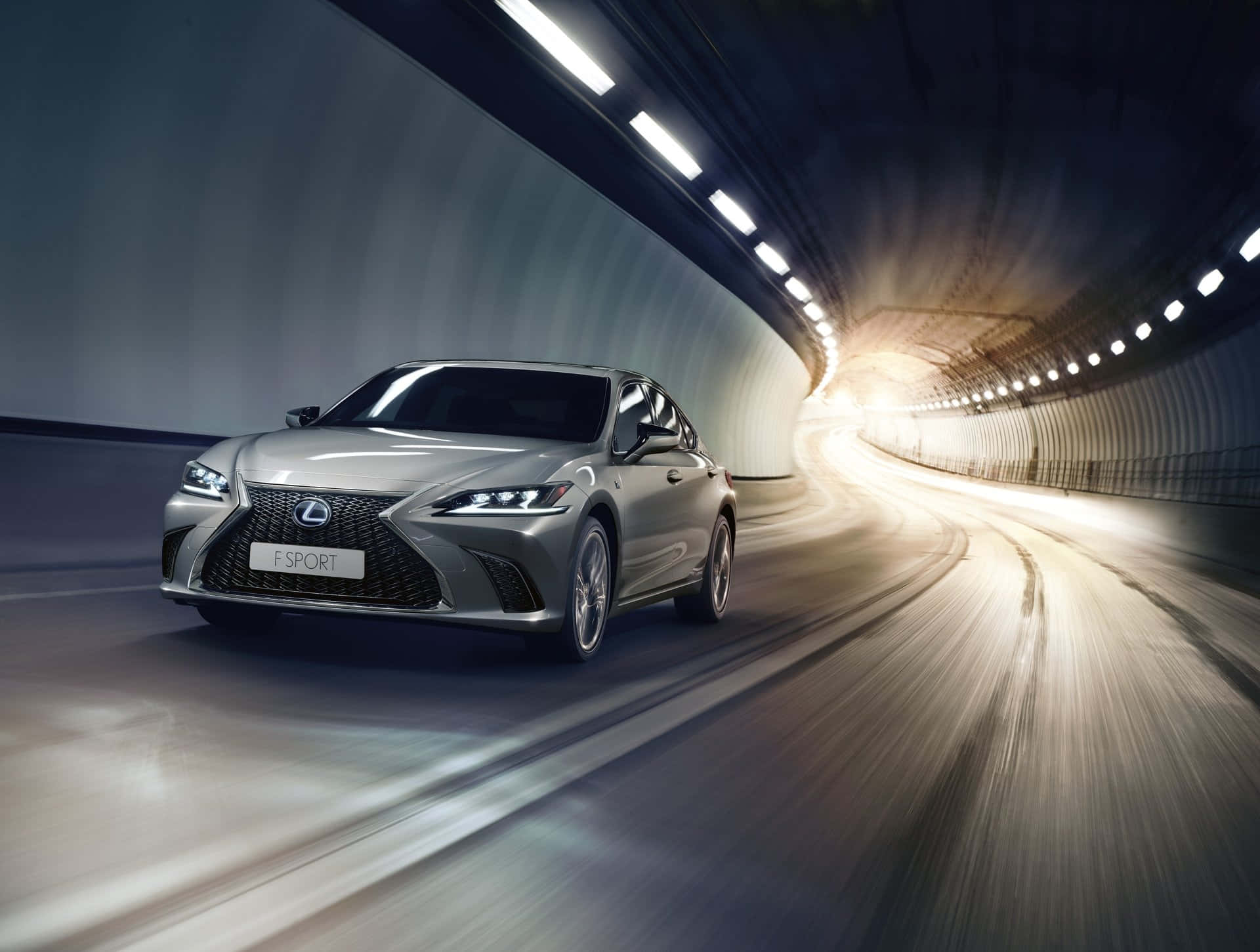 Lexus Es 300h 桌布 壁紙 — 一輛銀色 Lexus F SPORT 房車在彎曲隧道中高速行駛，帶有動態模糊效果和明亮的頭頂燈光。
