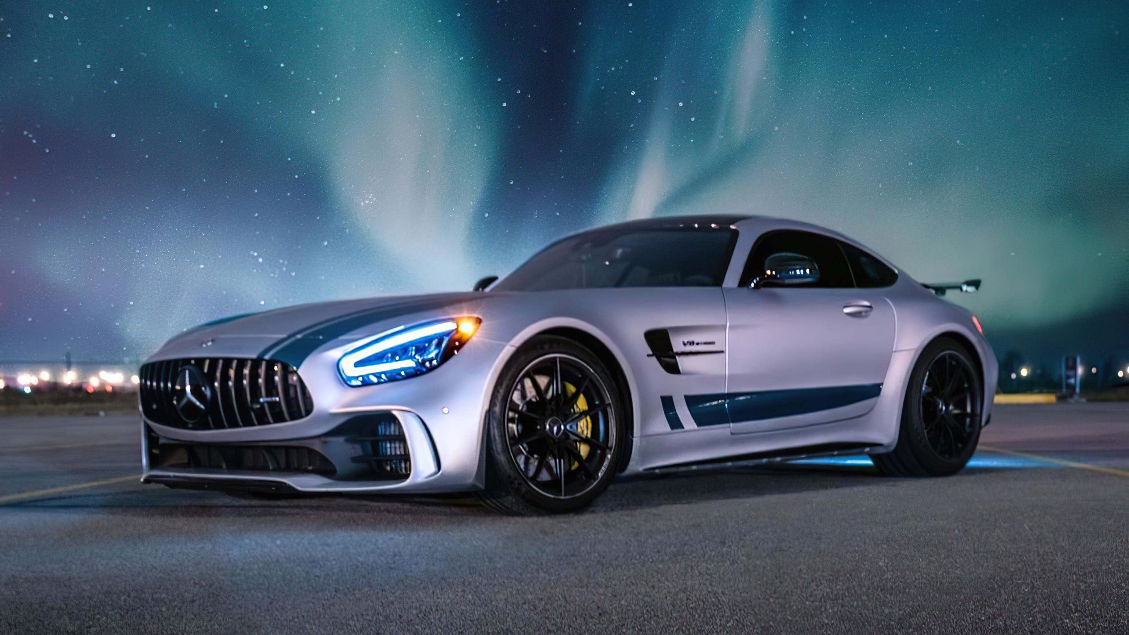 Gtr 桌布 壁紙 — 一輛銀色 Mercedes-AMG GT Black Series 跑車在繁星點點的夜空下，於充滿活力的綠色極光中閃耀。