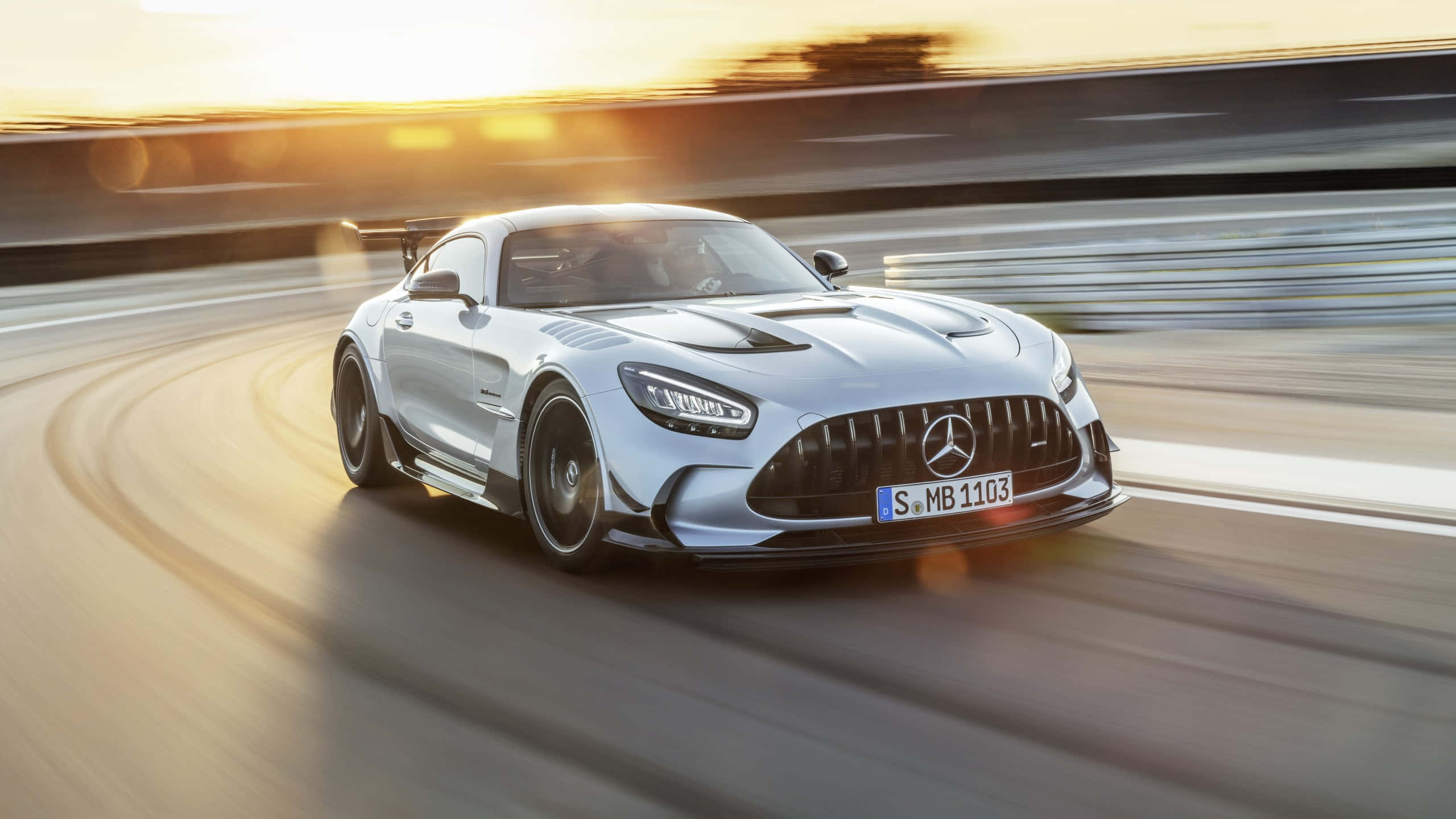 桌布 壁紙 — 一輛銀色 Mercedes-AMG GT R 賽車在日落時分於賽道上疾馳，背景呈現動態模糊效果。