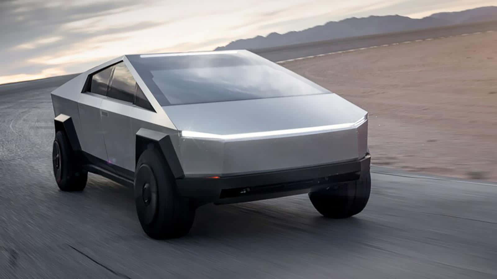 Tesla Cybertruck 桌布 壁紙 — 一輛銀色 Tesla Cybertruck 在沙漠公路上疾駛，背景是山脈，天空呈現柔和的暮色。