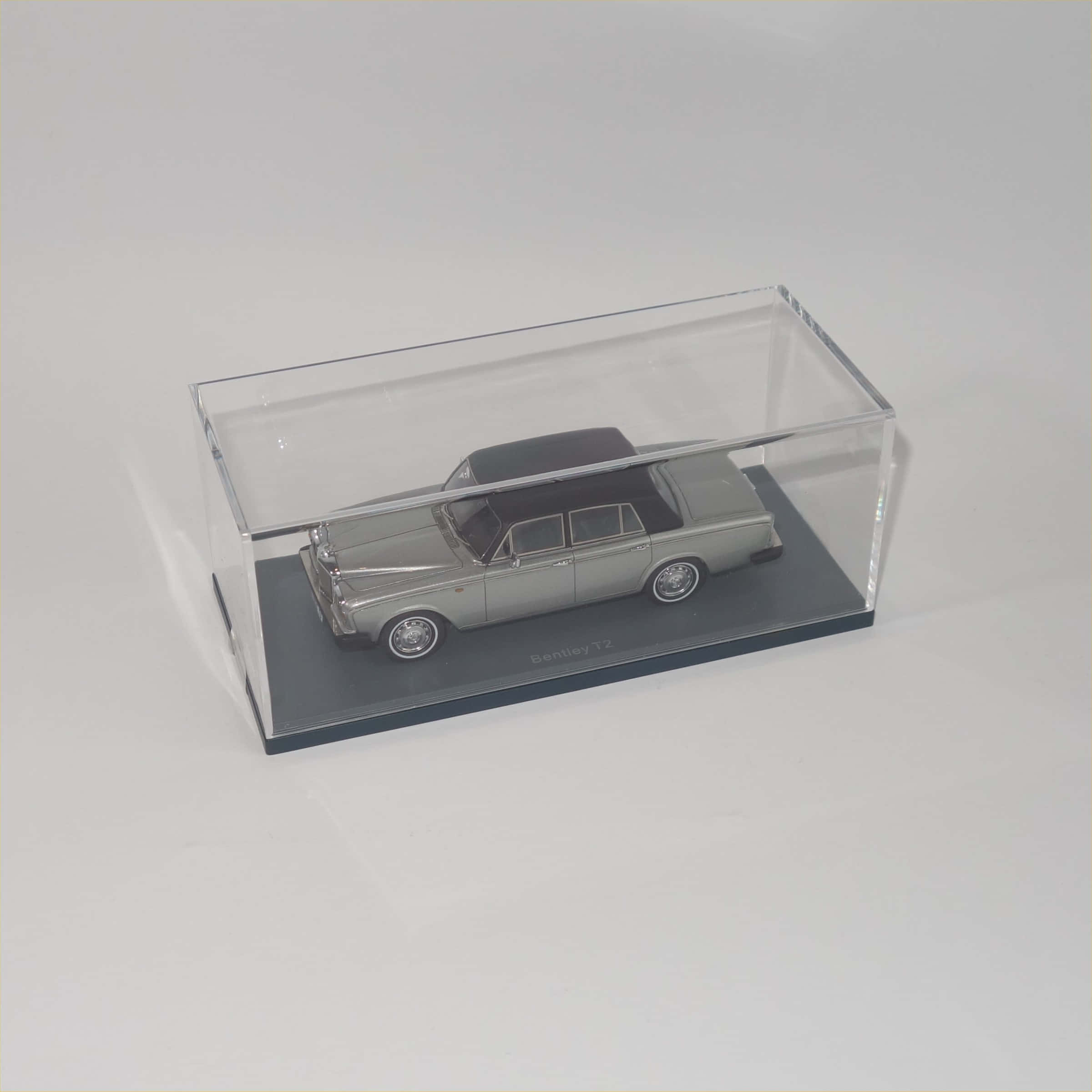 Bentley T2 桌布 壁紙 — 一輛銀色Bentley T2模型車，黑色車頂，展示在灰色底座上的透明壓克力盒中。