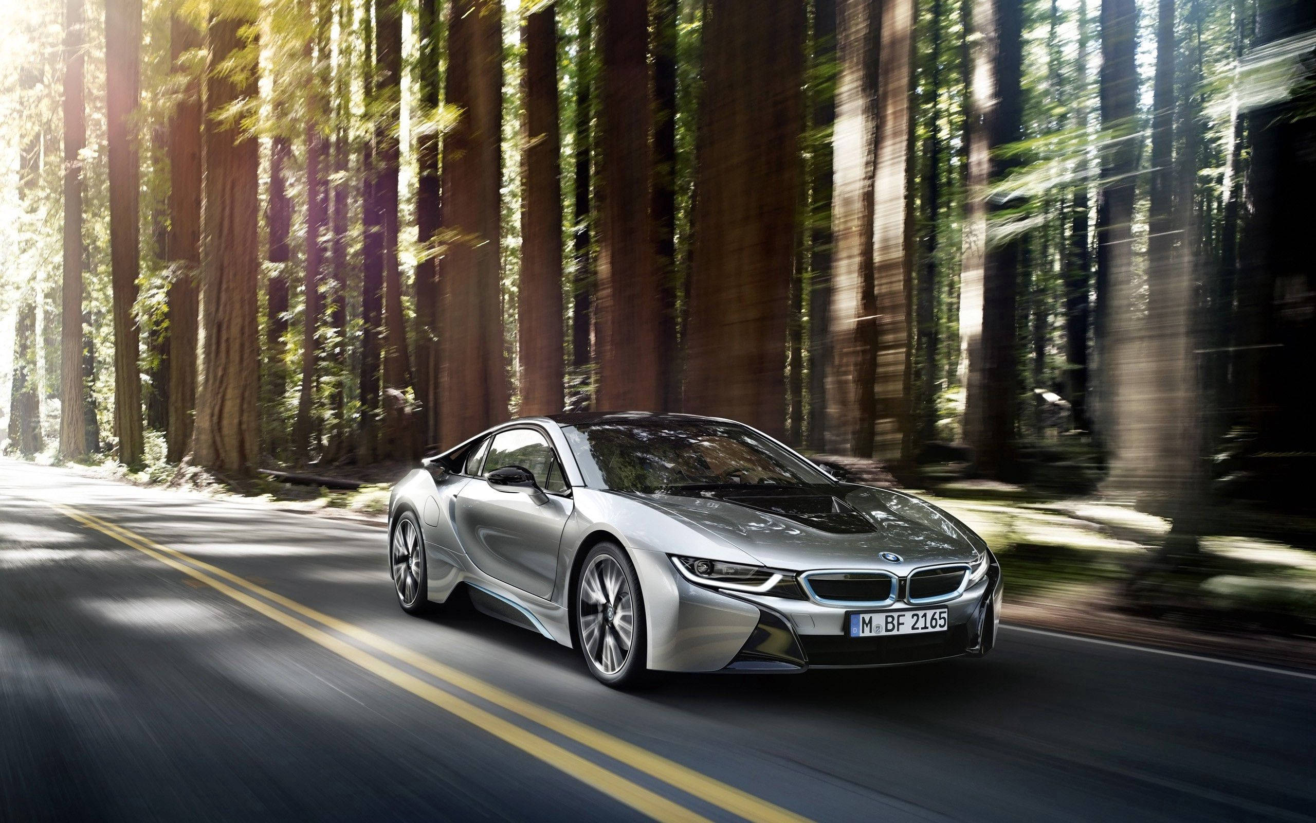 銀色 桌布 壁紙 — 一輛銀色BMW i8跑車在森林道路上疾駛，高大的樹木和斑駁的陽光造成動態模糊。