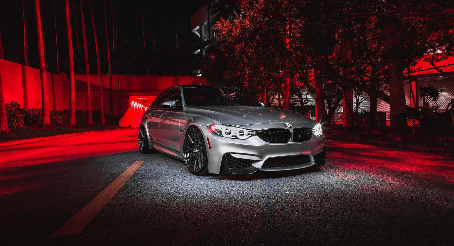BMW 動圖 桌布 壁紙 — 一輛銀色BMW M3跑車在夜間黑暗的城市街道上，在強烈的紅色霓虹燈下閃閃發光。