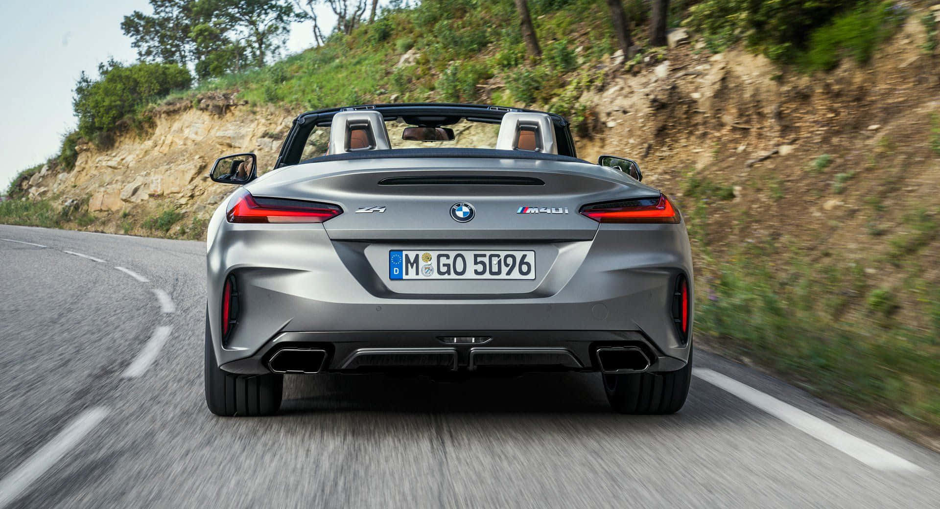 Bmw Z4 桌布 壁紙 — 一輛銀色BMW M4 Convertible在蜿蜒的山路上疾駛，兩旁是茂密的綠植和岩石峭壁。