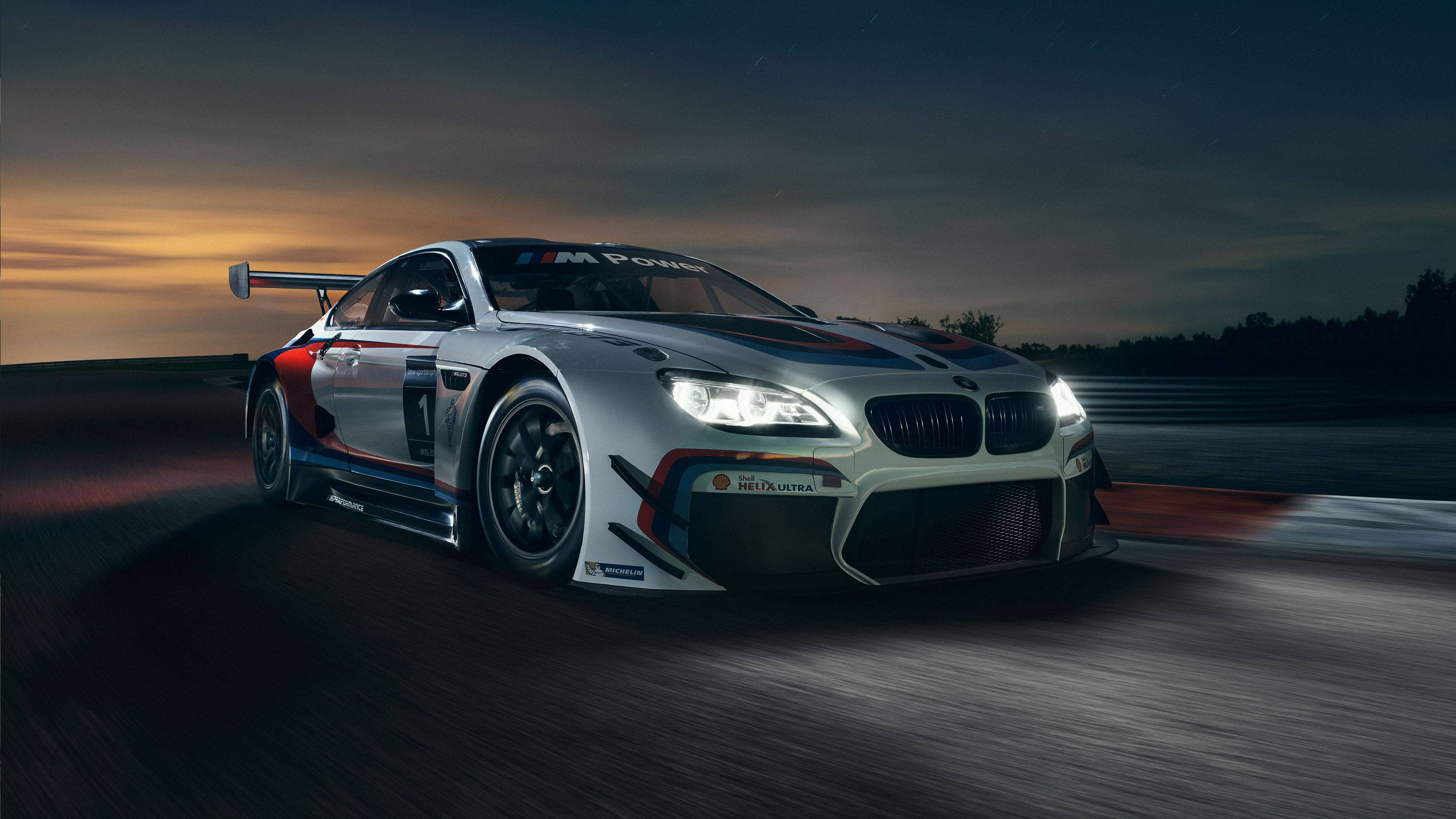 m 桌布 壁紙 — 一輛銀色BMW M6 GT3賽車在黃昏時分沿著賽道疾馳，車頭燈閃爍，帶有動態模糊效果。