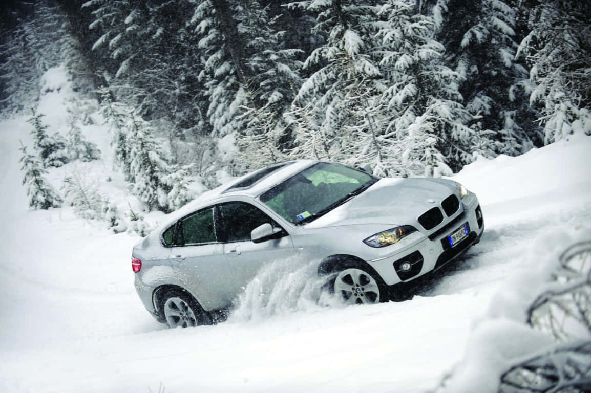 Winter Driving 桌布 壁紙 — 一輛銀色BMW X6在白雪覆蓋的松樹林中穿越深雪行駛。