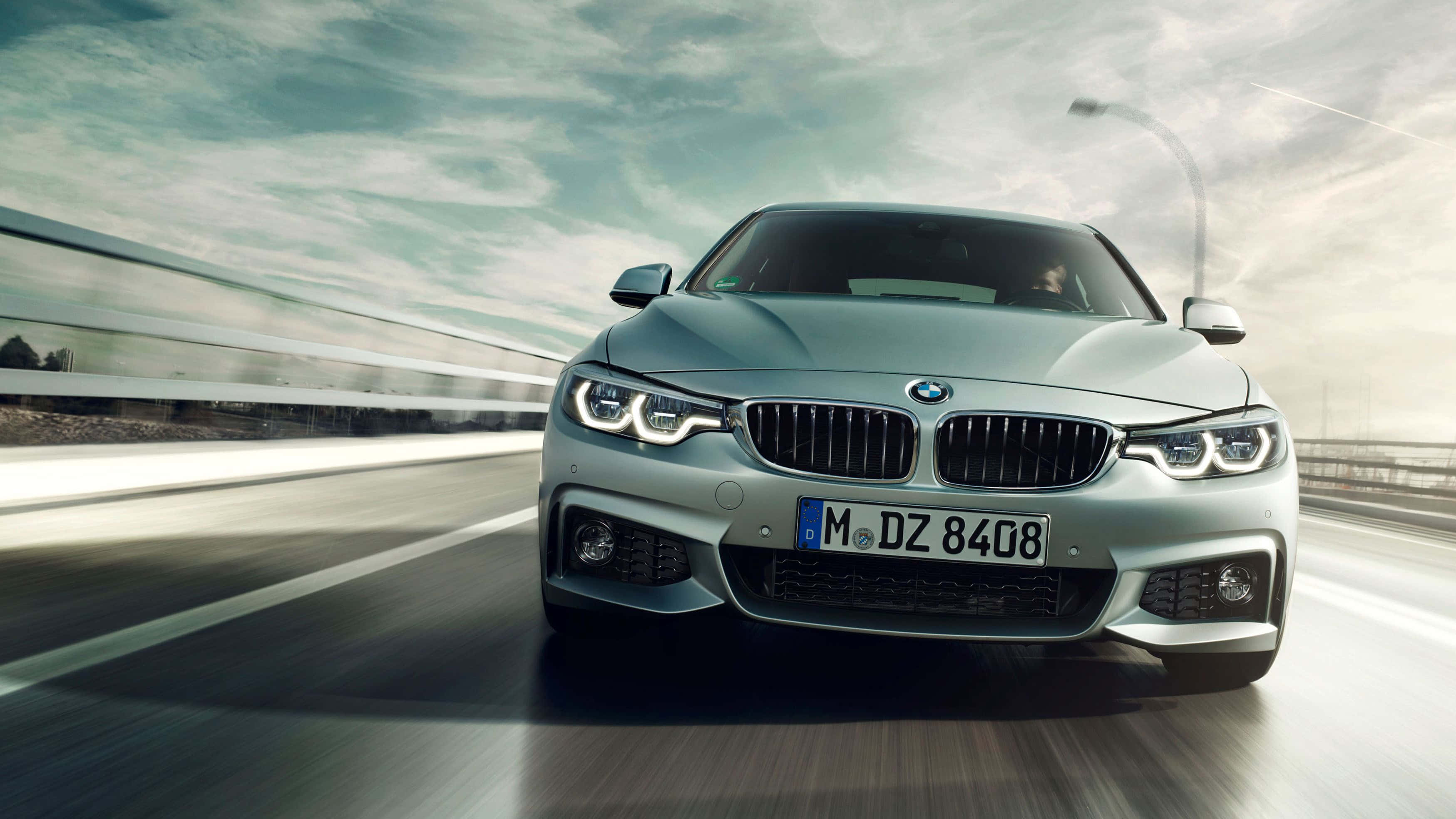 Bmw 4 Series 桌布 壁紙 — 一輛銀色BMW轎車在高速公路上疾馳，在陰天天空下帶有動態模糊效果。