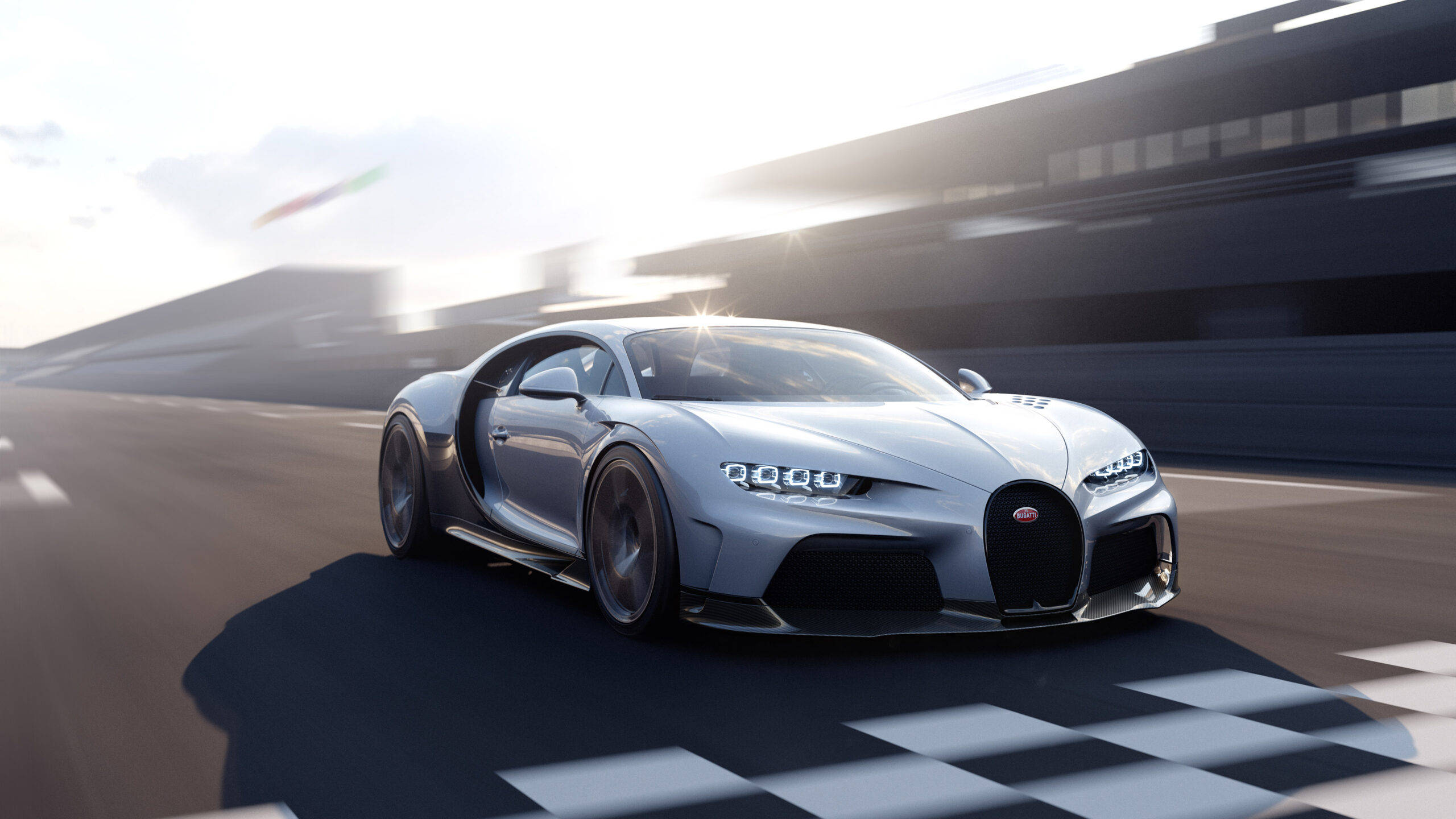 跑車 桌布 壁紙 — 一輛銀色Bugatti Chiron在陽光普照的賽車道上，背景帶有動態模糊效果，飛馳越過方格旗終點線。