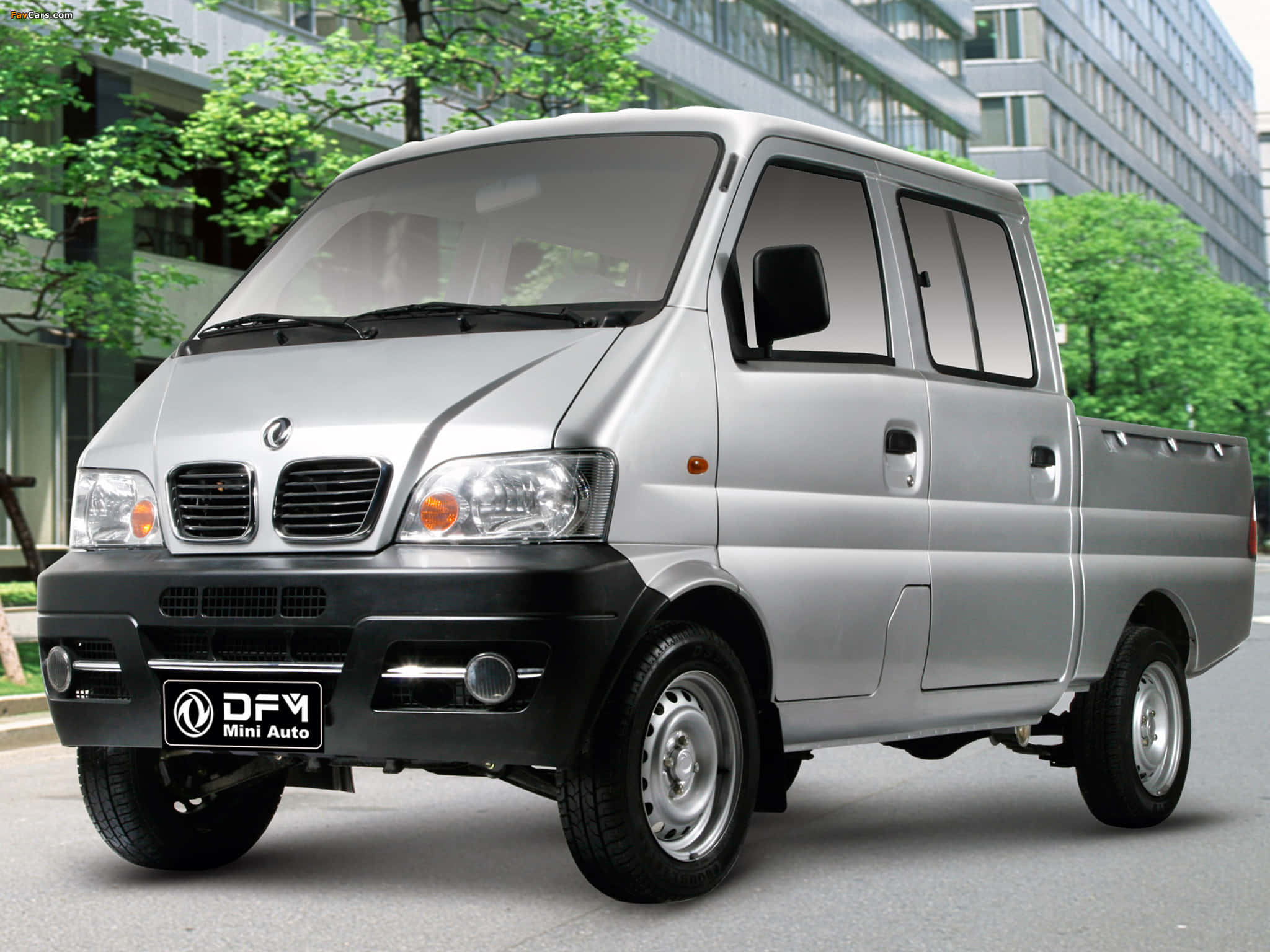 Dongfeng 桌布 壁紙 — 一輛銀色DFY Mini Auto小型貨車停放在城市的街道上，背景有綠樹和現代建築。