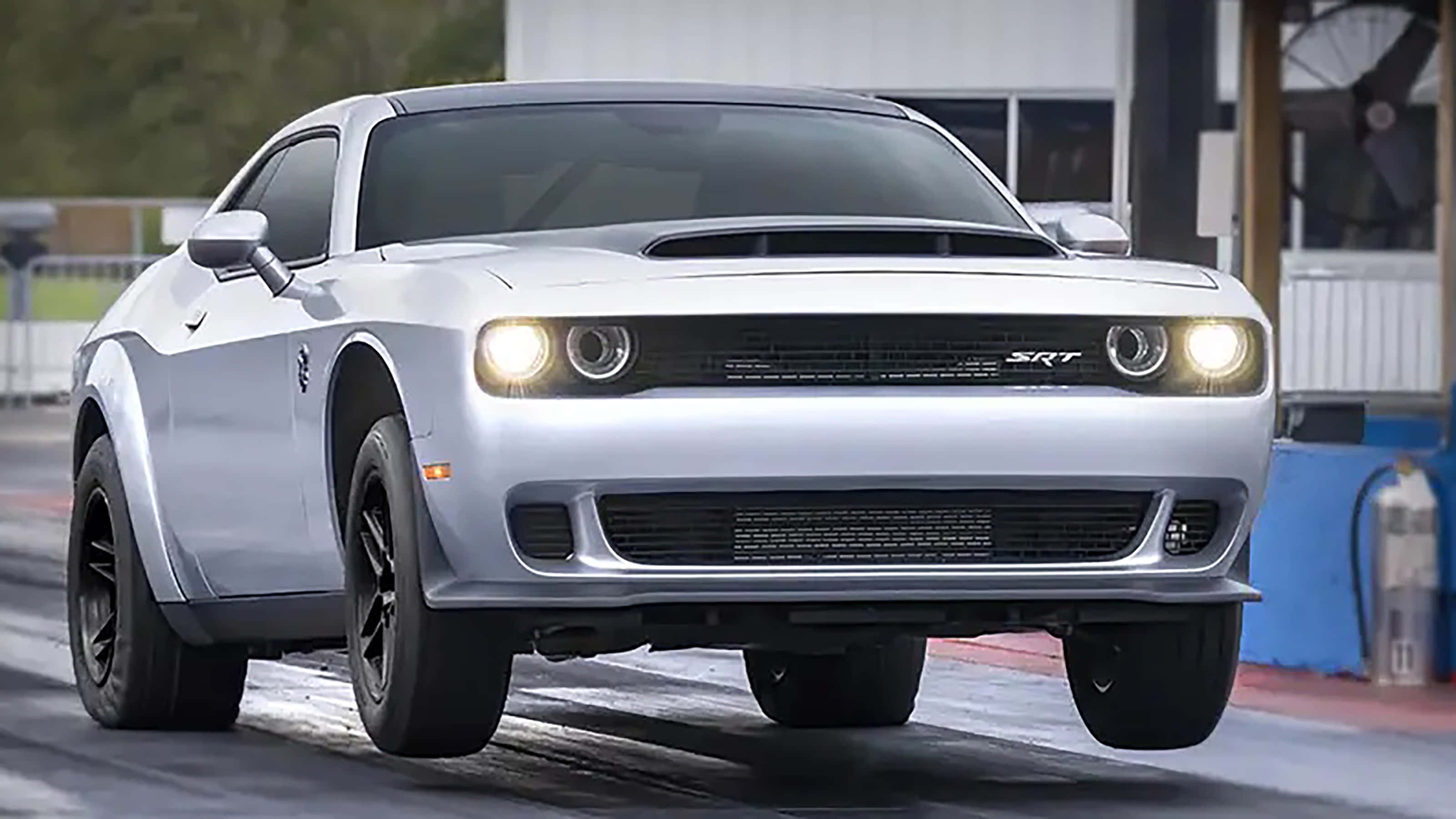 Dodge 桌布 壁紙 — 一輛銀色Dodge Challenger SRT在潮濕的直線加速賽道上奔馳，車頭燈亮起，輪胎濺起水花。