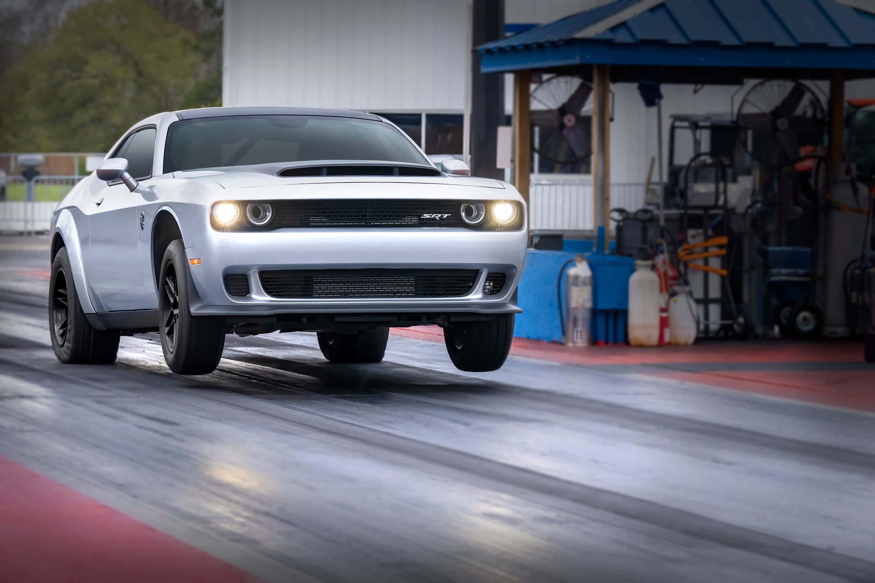 道奇 桌布 壁紙 — 一輛銀色Dodge Challenger SRT在潮濕的直線加速賽道上奔馳，車頭燈閃耀，輪胎留下動態模糊的痕跡。