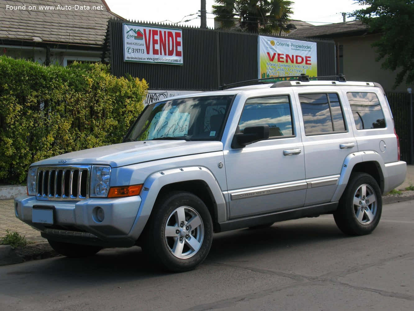 Jeep Commander 桌布 壁紙 — 一輛銀色Jeep Cherokee SUV停放在街上，旁邊有綠色灌木叢和帶有「Vende」標誌的圍籬。