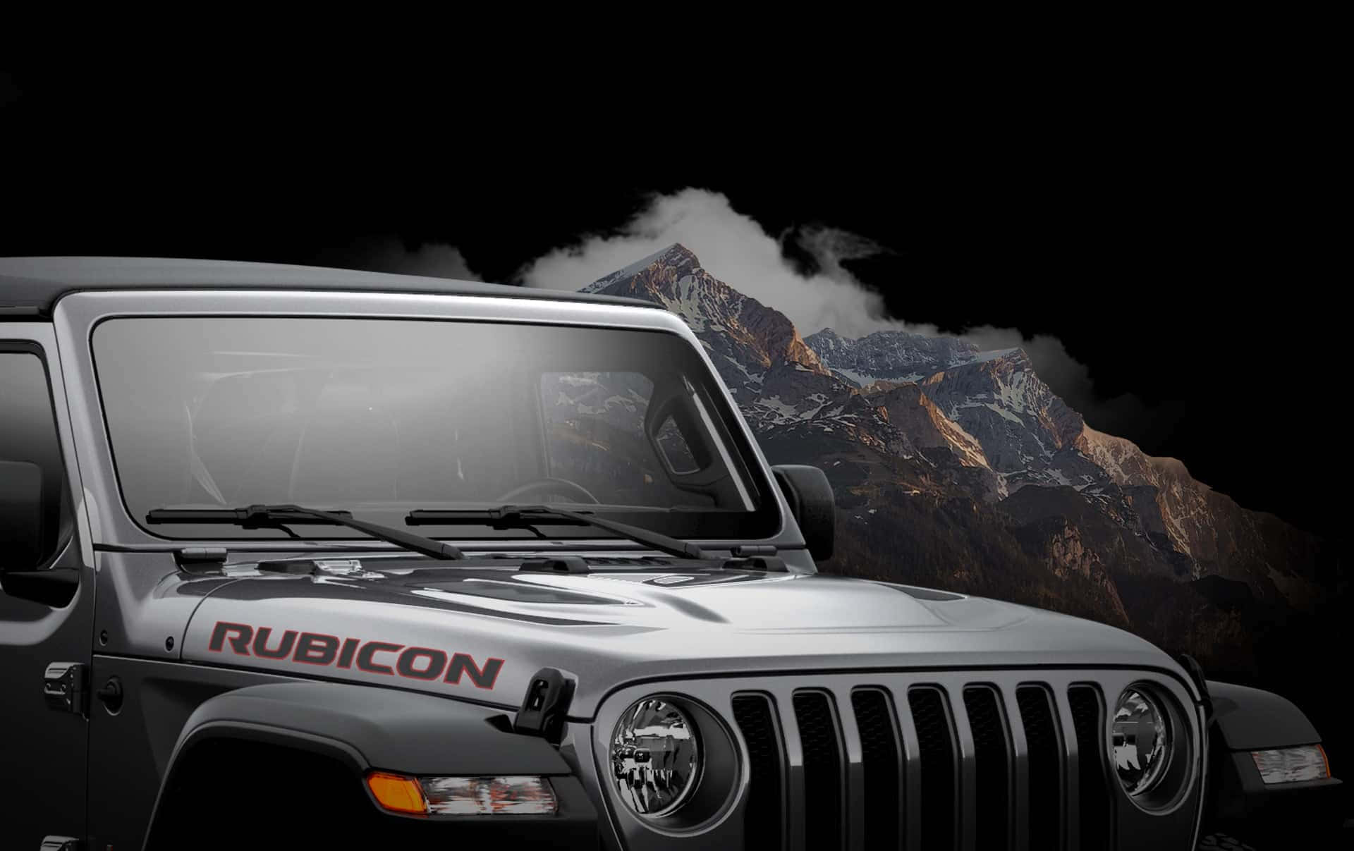 吉普 桌布 壁紙 — 一輛銀色Jeep Rubicon SUV主導前景，背後戲劇性的山峰在黑暗的天空下升起。