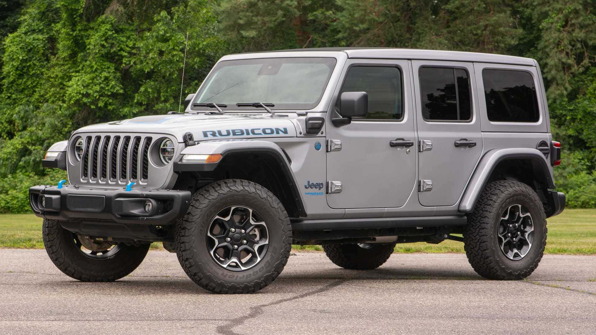 吉普 桌布 壁紙 — 一輛銀色Jeep Wrangler Rubicon停在柏油路面上，背景是茂密的綠樹。