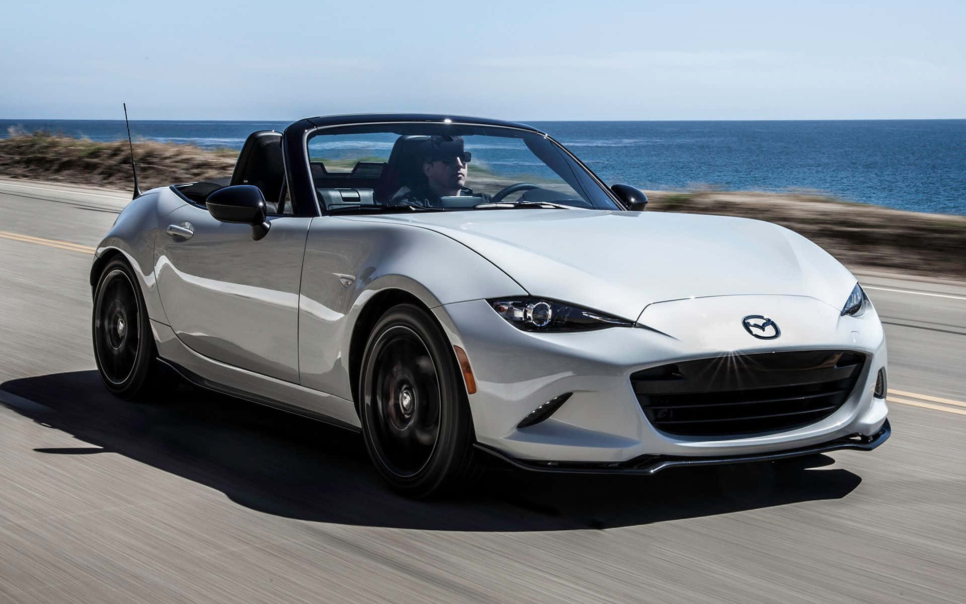 跑車 桌布 壁紙 — 一輛銀色Mazda MX-5 Miata敞篷跑車沿海岸公路疾駛，背景是海洋。