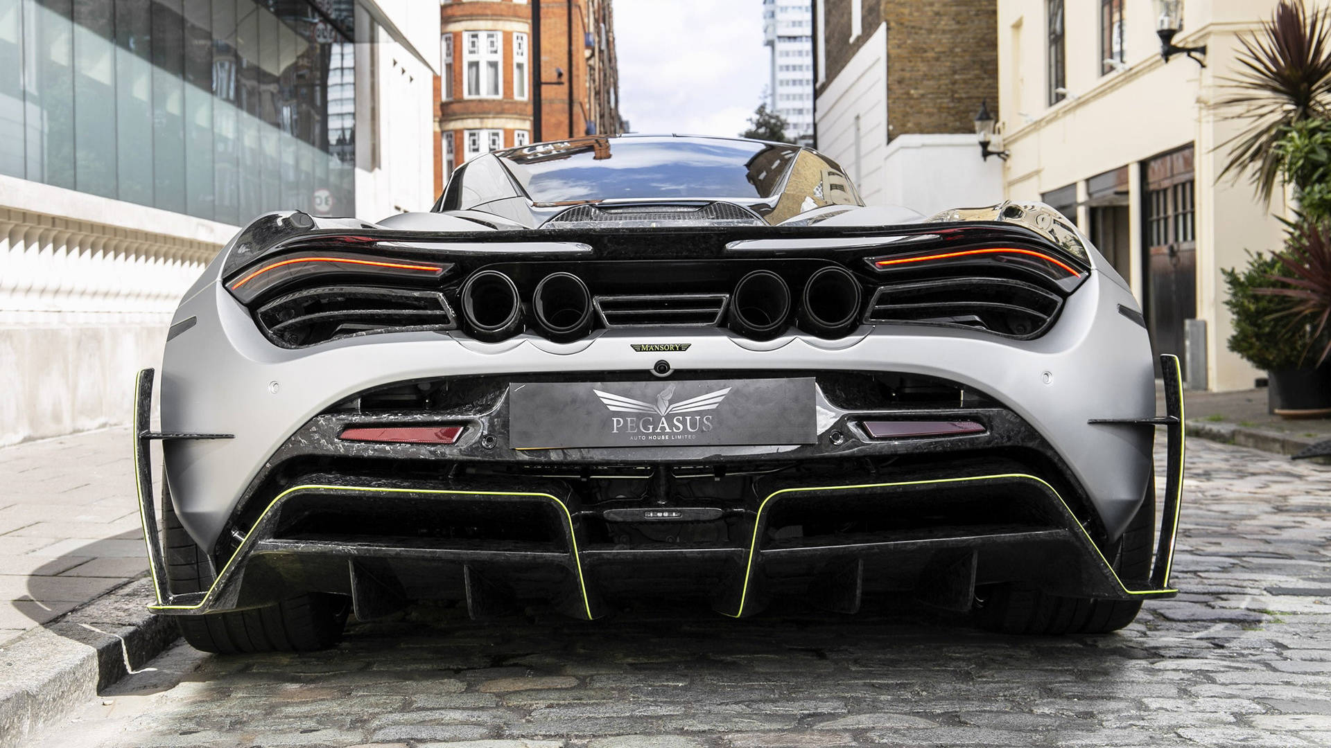 mclaren 720s 4K 桌布 壁紙 — 一輛銀色McLaren Pegasus超跑帶有黃色點綴，停泊在都市建築之間的鵝卵石街道上。