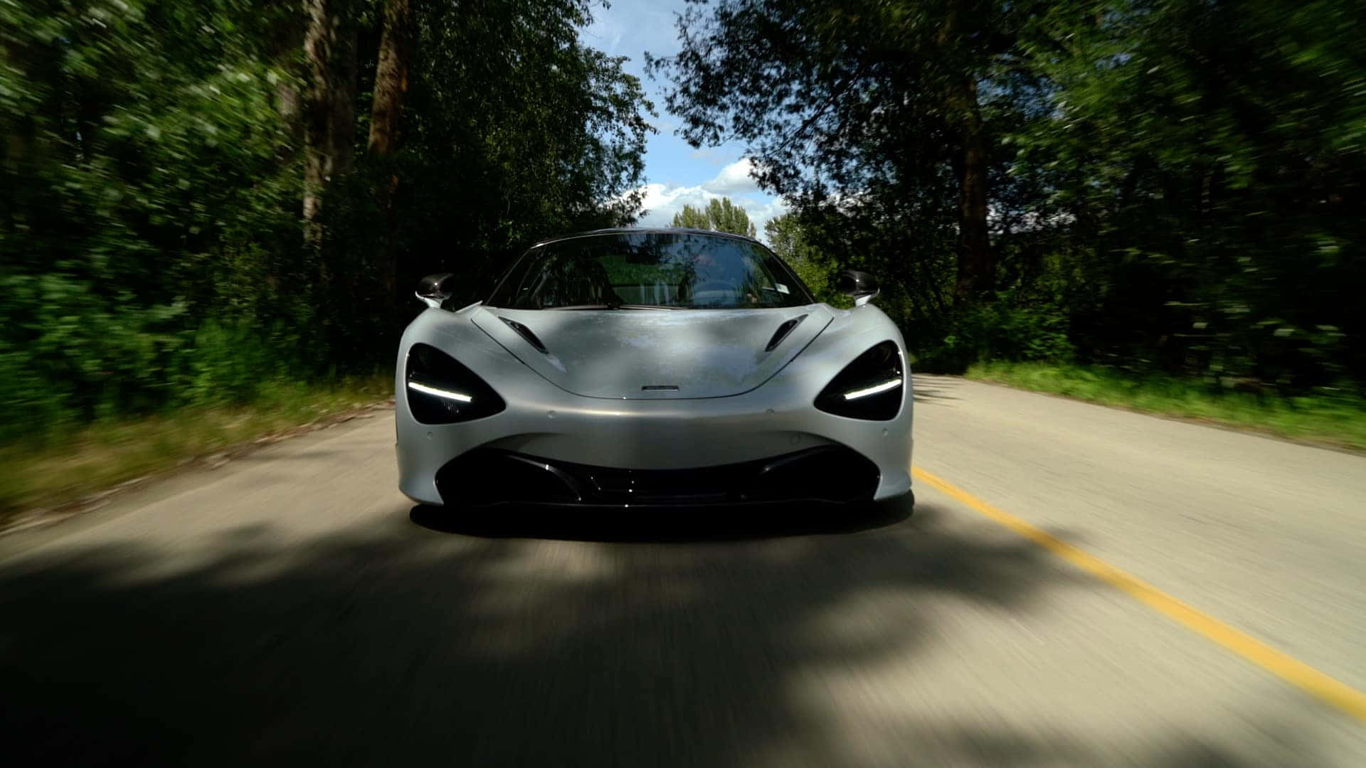 trees 桌布 壁紙 — 一輛銀色McLaren跑車在兩旁樹木成蔭的道路上高速行駛，周圍環境呈現動態模糊效果。