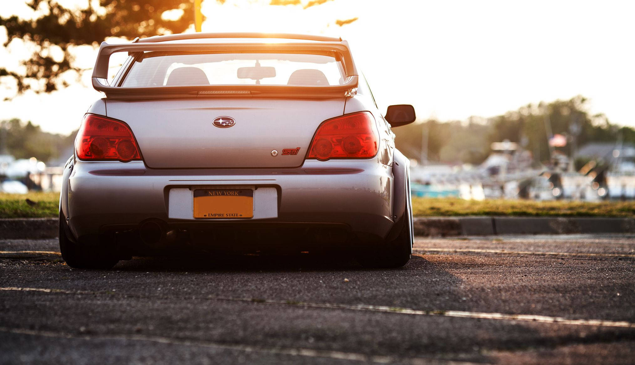 昴 桌布 壁紙 — 一輛銀色Subaru WRX STI停放在柏油路上，金色夕陽在其後方投射出長長的影子。